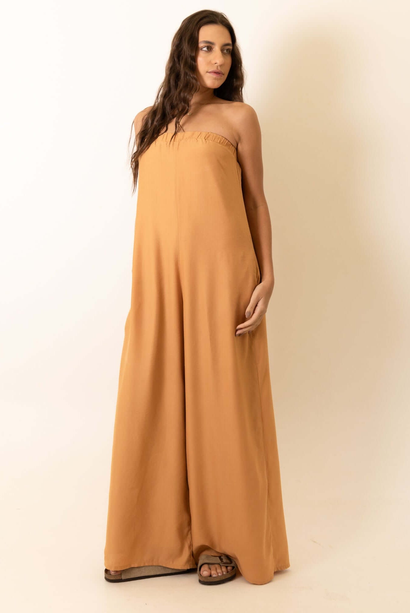 Mulher vestindo Macacão Leslie - Caqui da marca Greenish em estúdio, fundo branco.