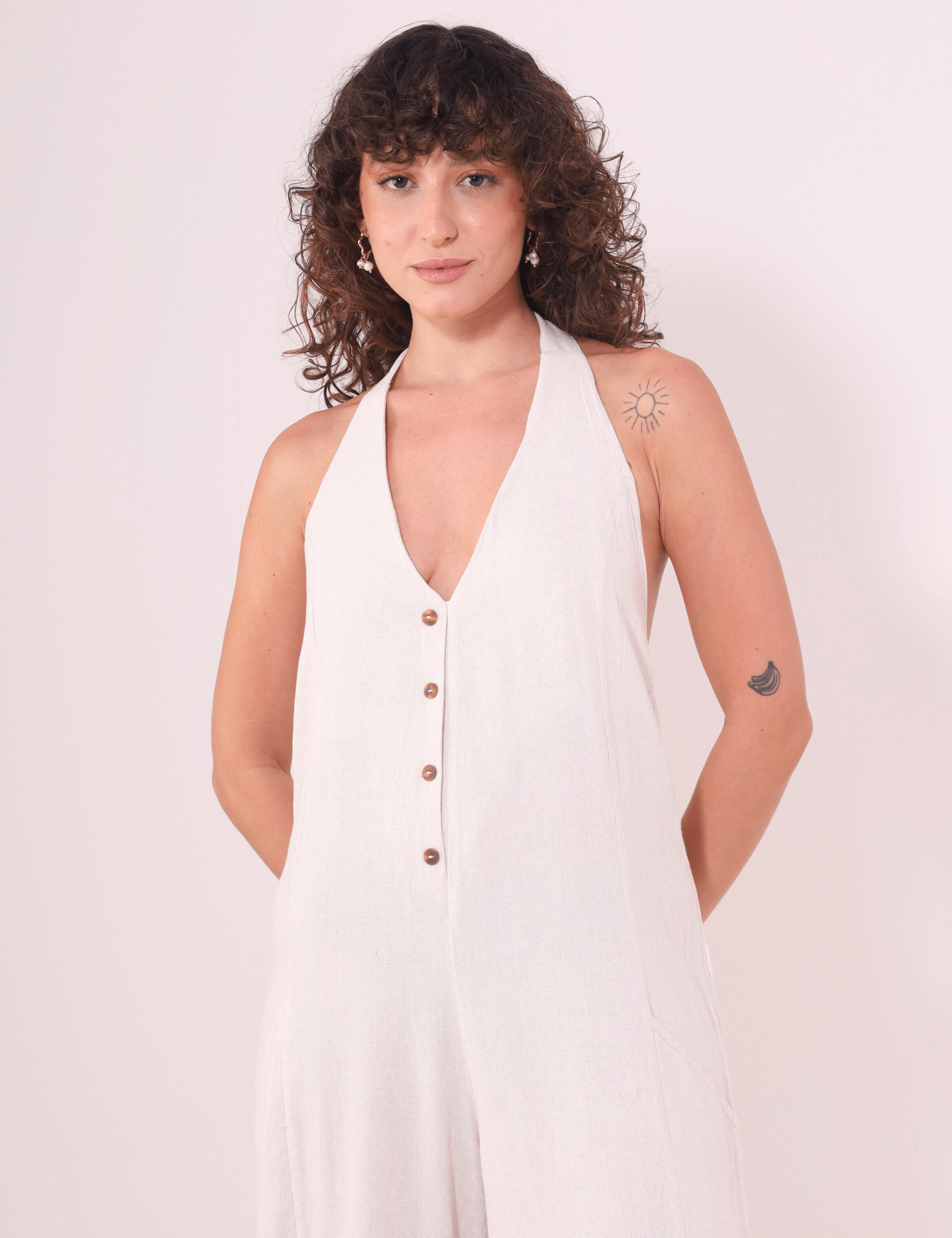 Modelo vestindo Macacão Longo Gaia - Natural da marca Greenish, com decote halter e botões decorativos, tecido Linho Washed Soft.