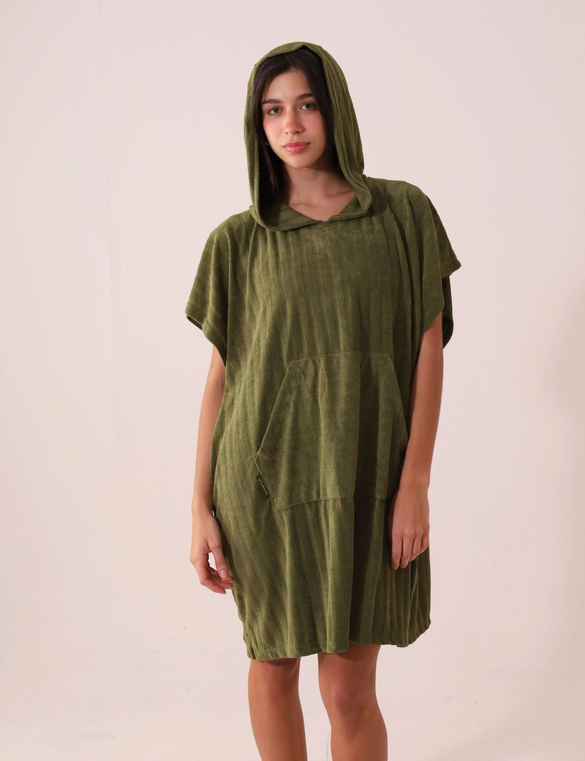 Mulher vestindo PONCHO CURTO CANELADO - VERDE da marca Greenish com capuz e bolso canguru, ideal para frio e esportes aquáticos.
