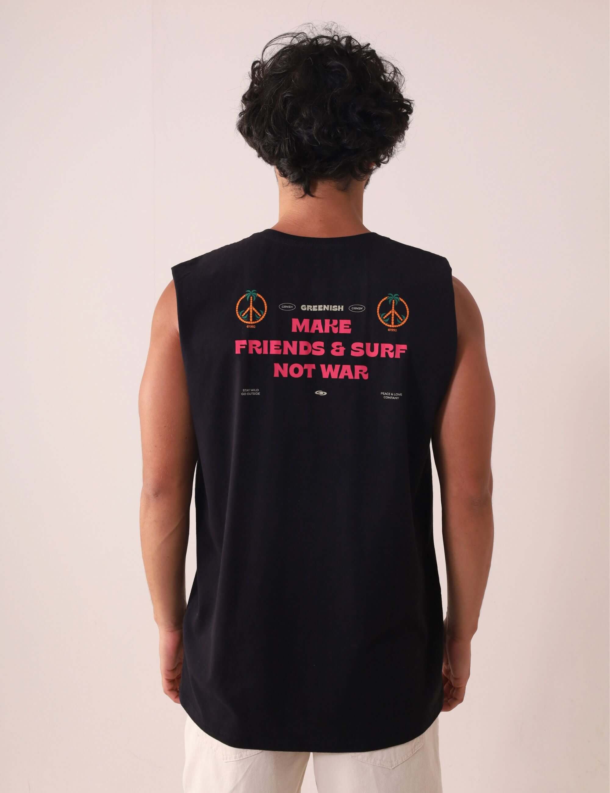Homem vestindo Regata Make Friends - Preto da marca Greenish com estampa "Make Friends & Surf Not War" nas costas, ideal para dias de sol.