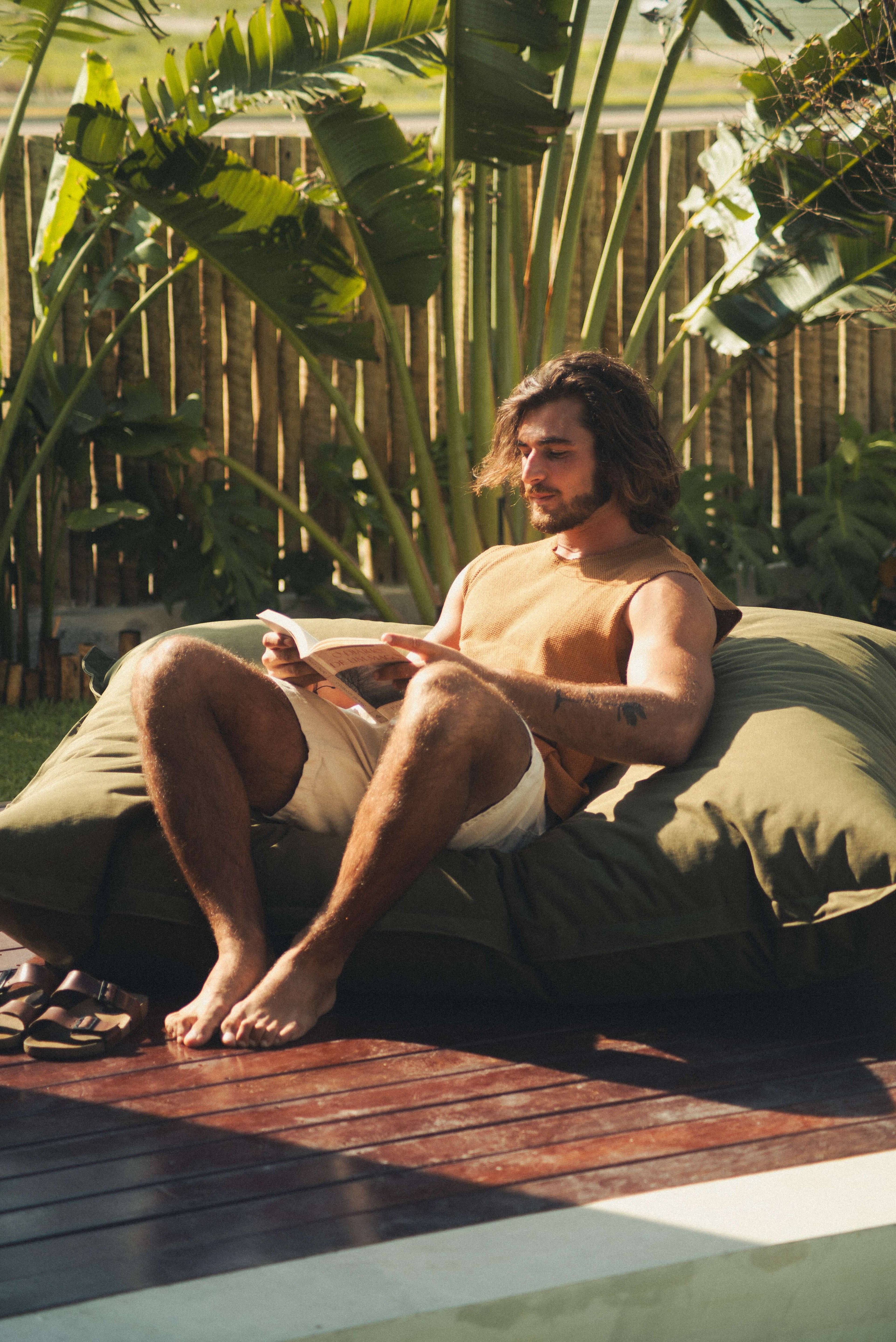 Homem relaxando ao sol, vestindo REGATA MARÉ - CAQUI da marca Greenish, ideal para dias de sol e liberdade.