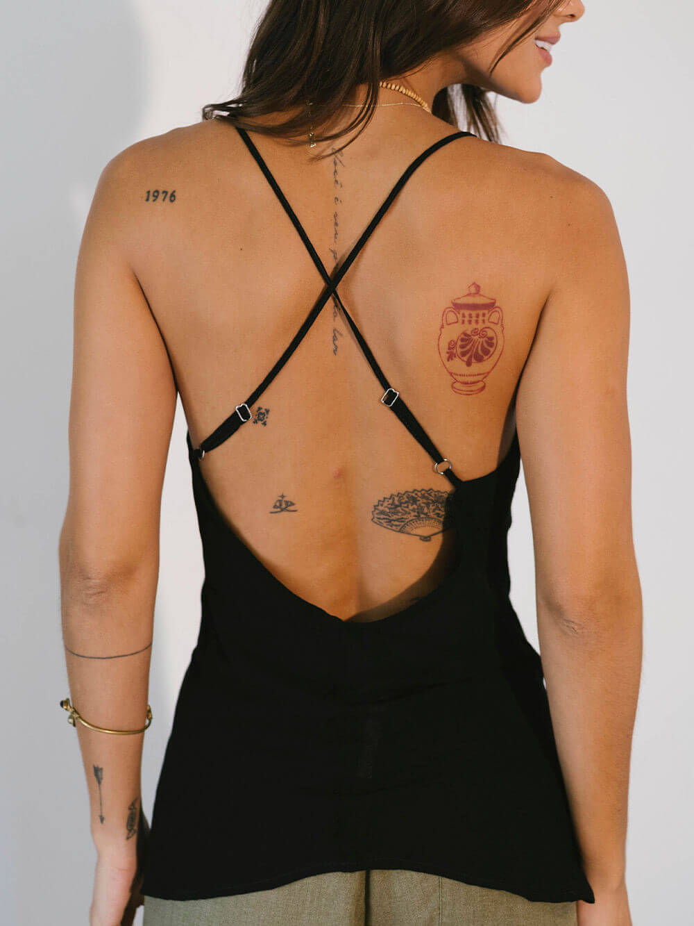 Modelo usando blusa preta Isla da Greenish, destaque para as alças finas e decote nas costas, estilo e conforto.