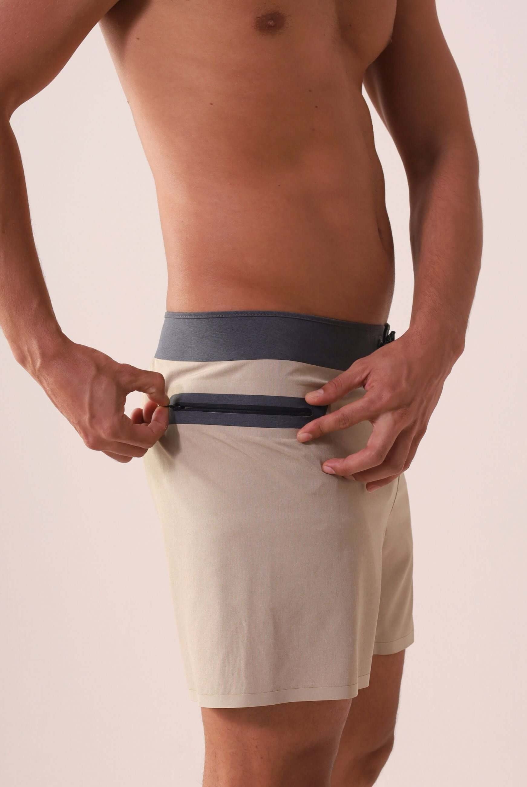 Homem usando o Boardshort Ultralight II Color - Caqui da Greenish, destacando o bolso com zíper para conforto e performance no surfe.