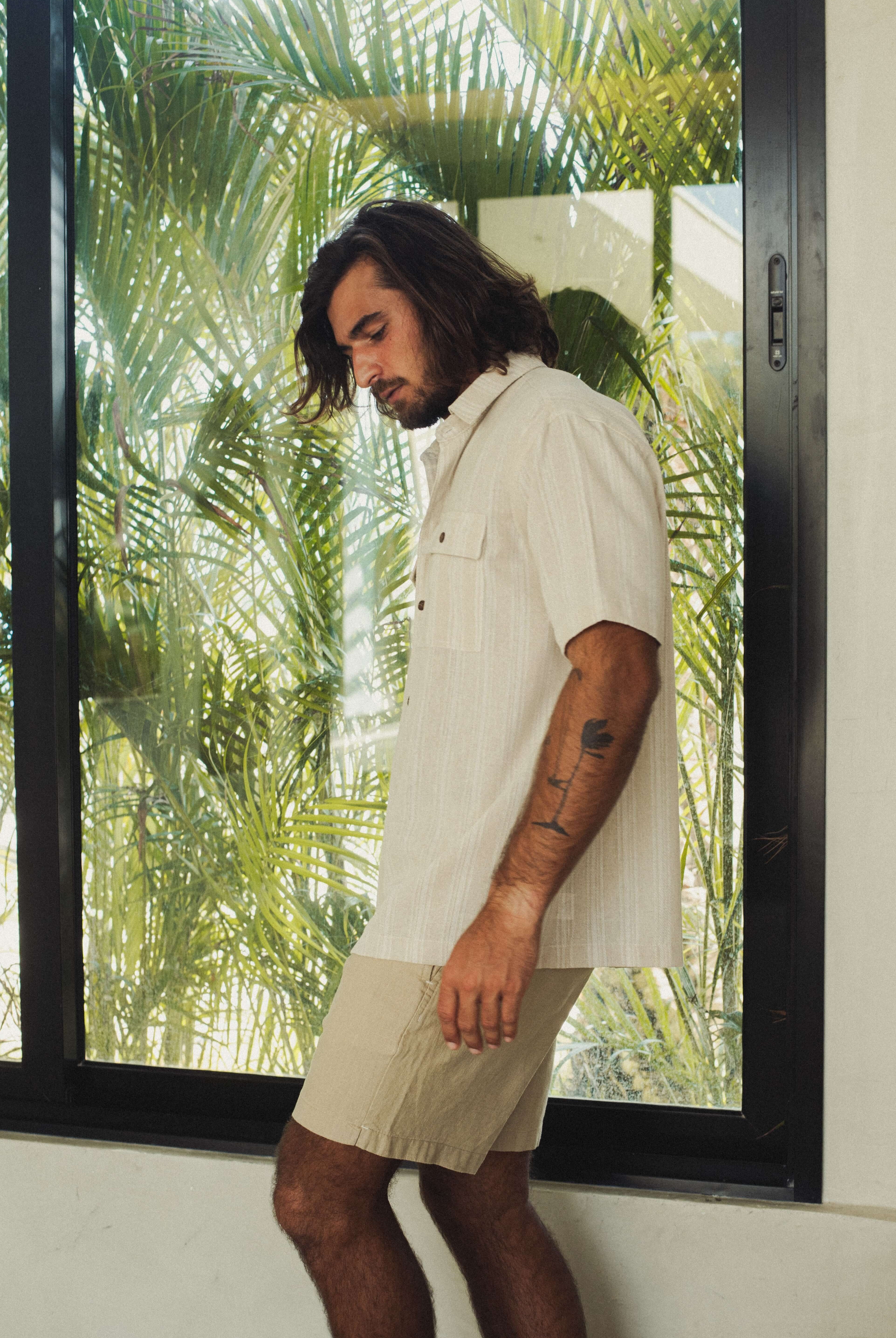 Modelo usando Camisa Botão Linho Listrado Oversized - Natural da marca Greenish em ambiente tropical.