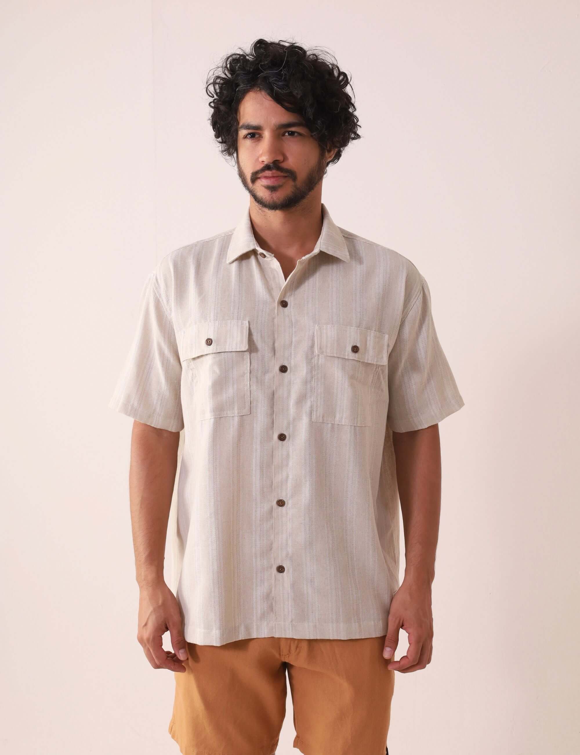 Homem vestindo Camisa Botão Linho Listrado Oversized - Natural da marca Greenish, exibindo estilo casual e sofisticado ao ar livre.