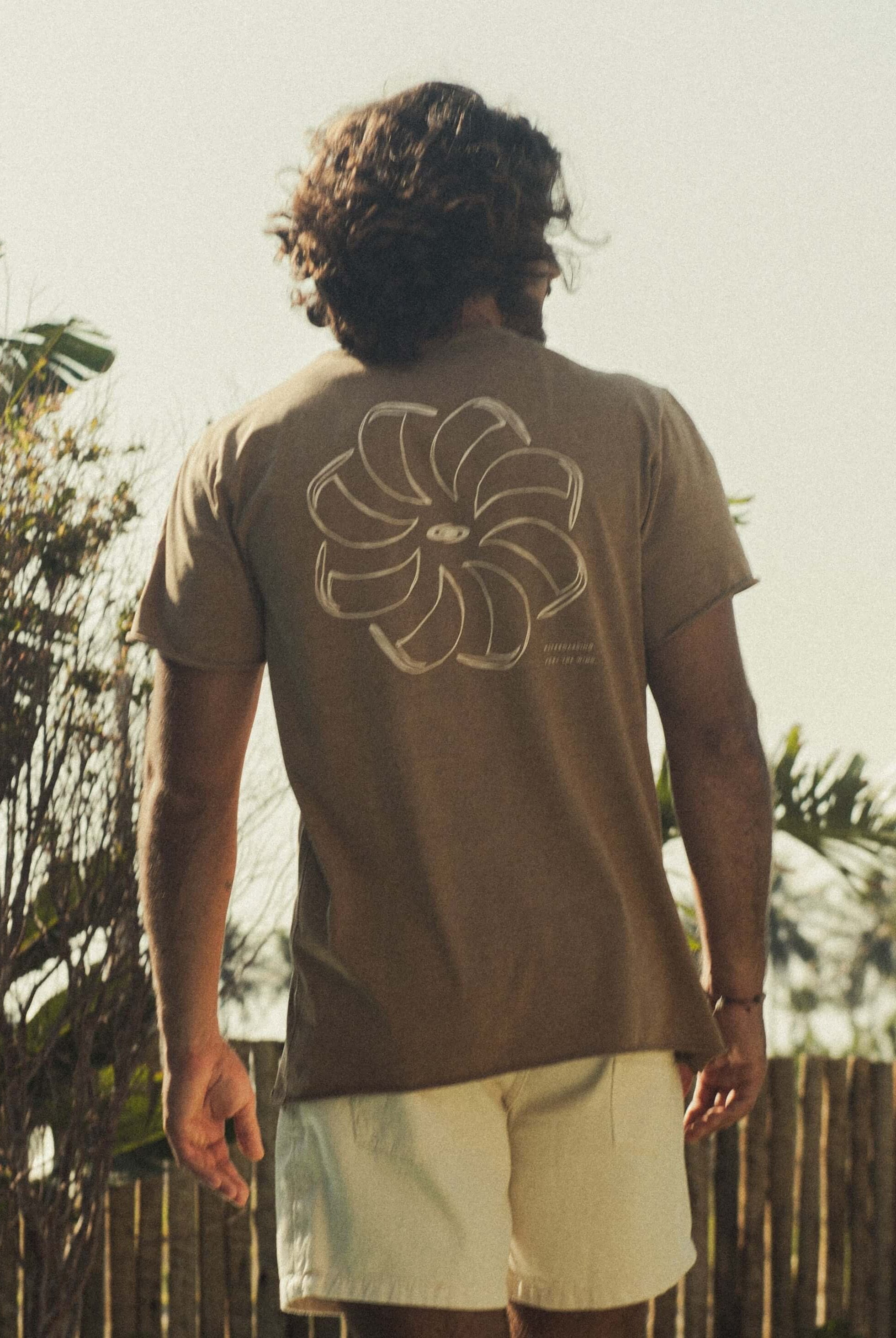 Camiseta Stone Feel The Winds - Marrom da Greenish, modelo básico em meia malha 100% algodão, vista de costas em ambiente natural.