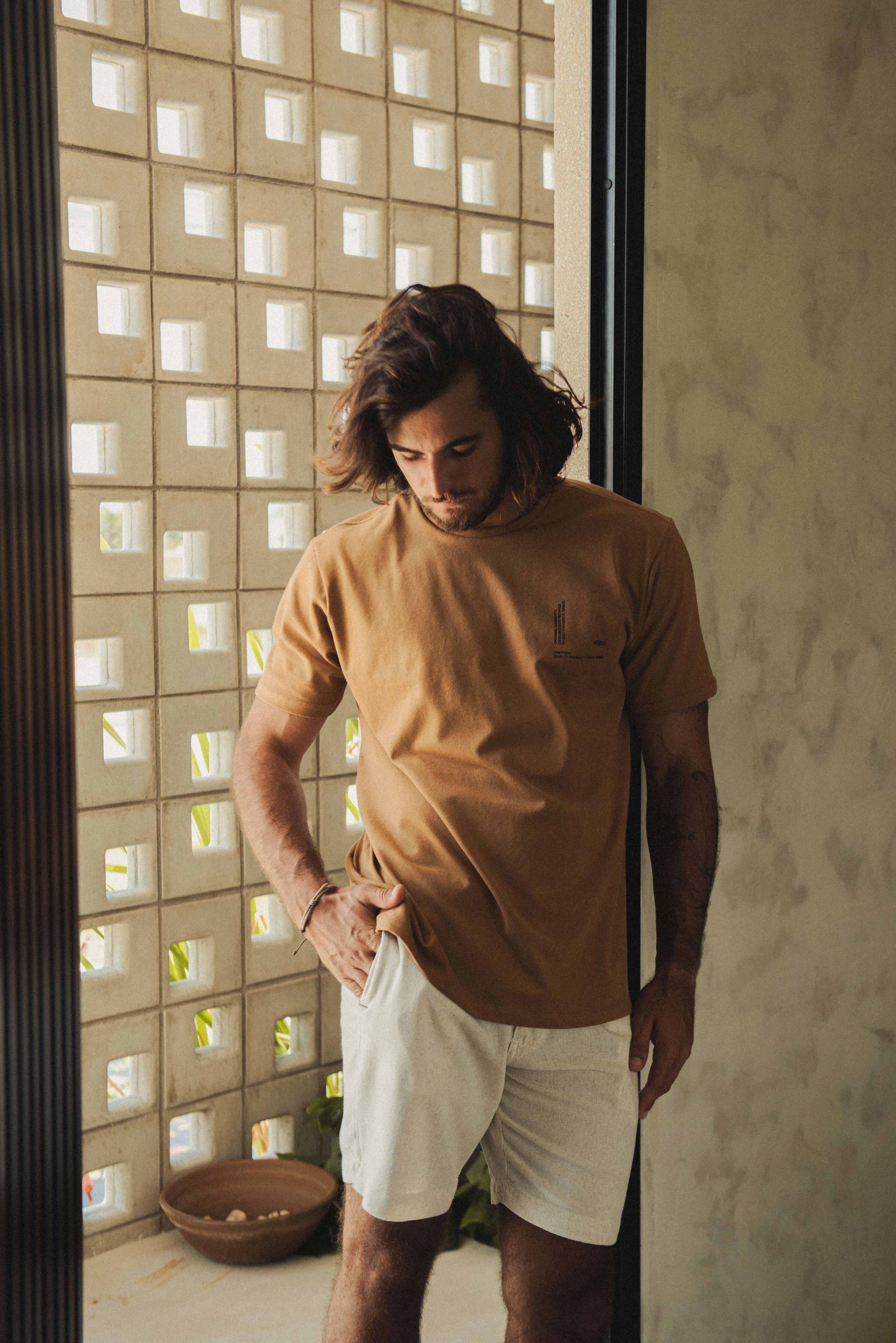 Homem usando Camiseta Greenish Quality Product - Caqui com design minimalista, ideal para o dia a dia, em um ambiente casual.