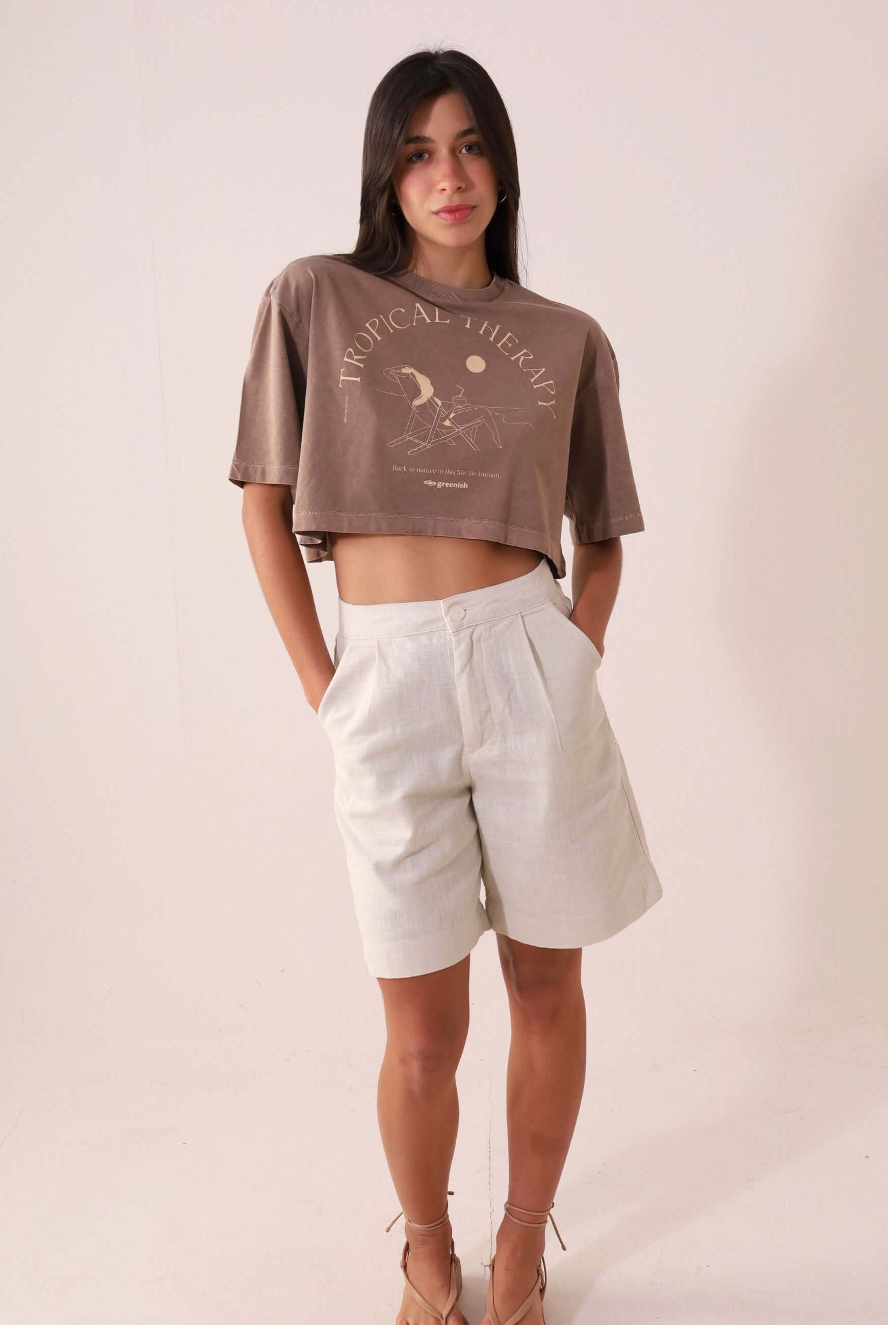 Modelo vestindo camiseta Greenish CROPPED STONE RELAXING VIEW - MARRON com estampa "Tropical Therapy", estilo casual e descontraído.