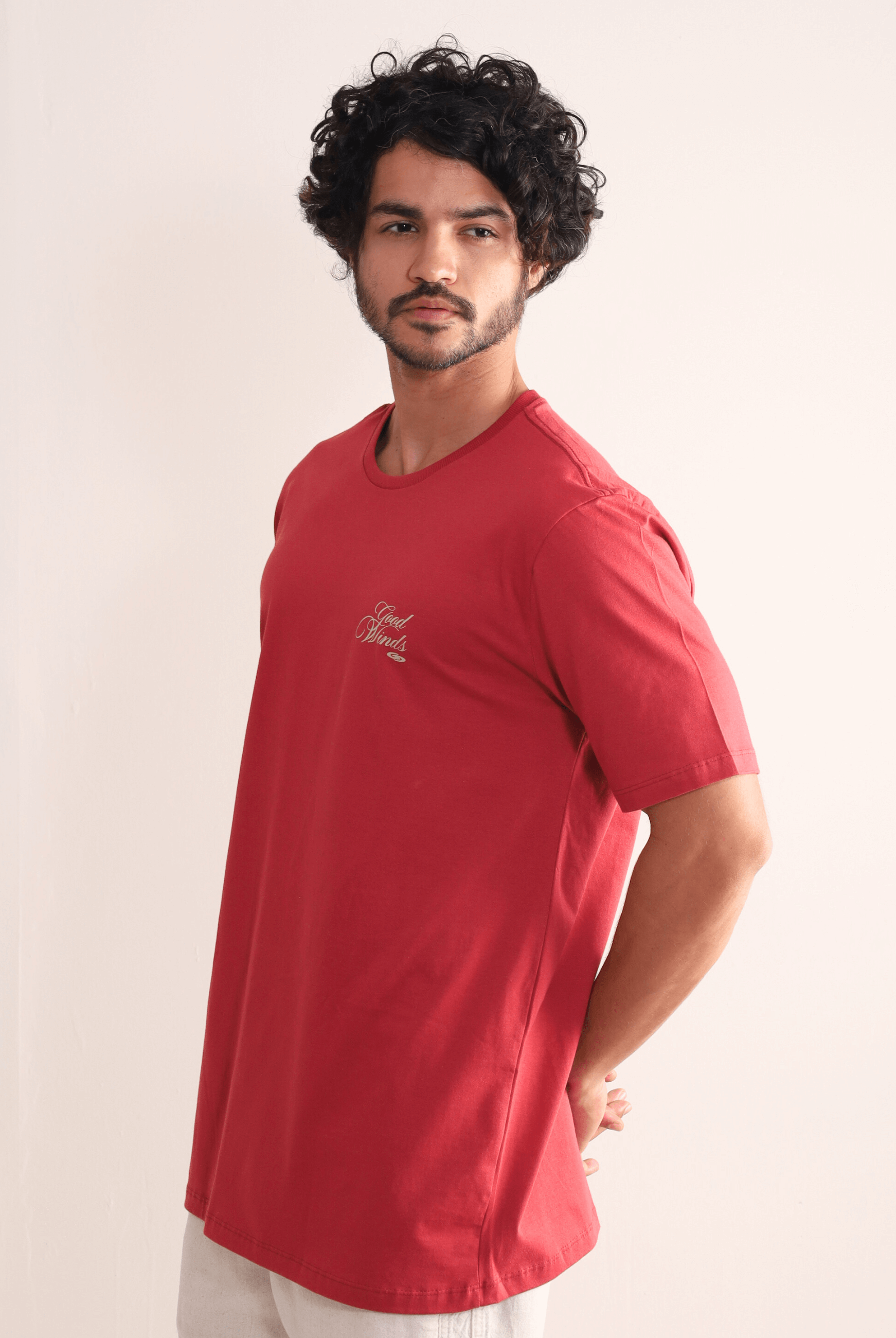 Homem usando Camiseta Vermelha Greenish "Kites & Good Winds", com bordado frontal. Conforto e estilo em algodão de qualidade.