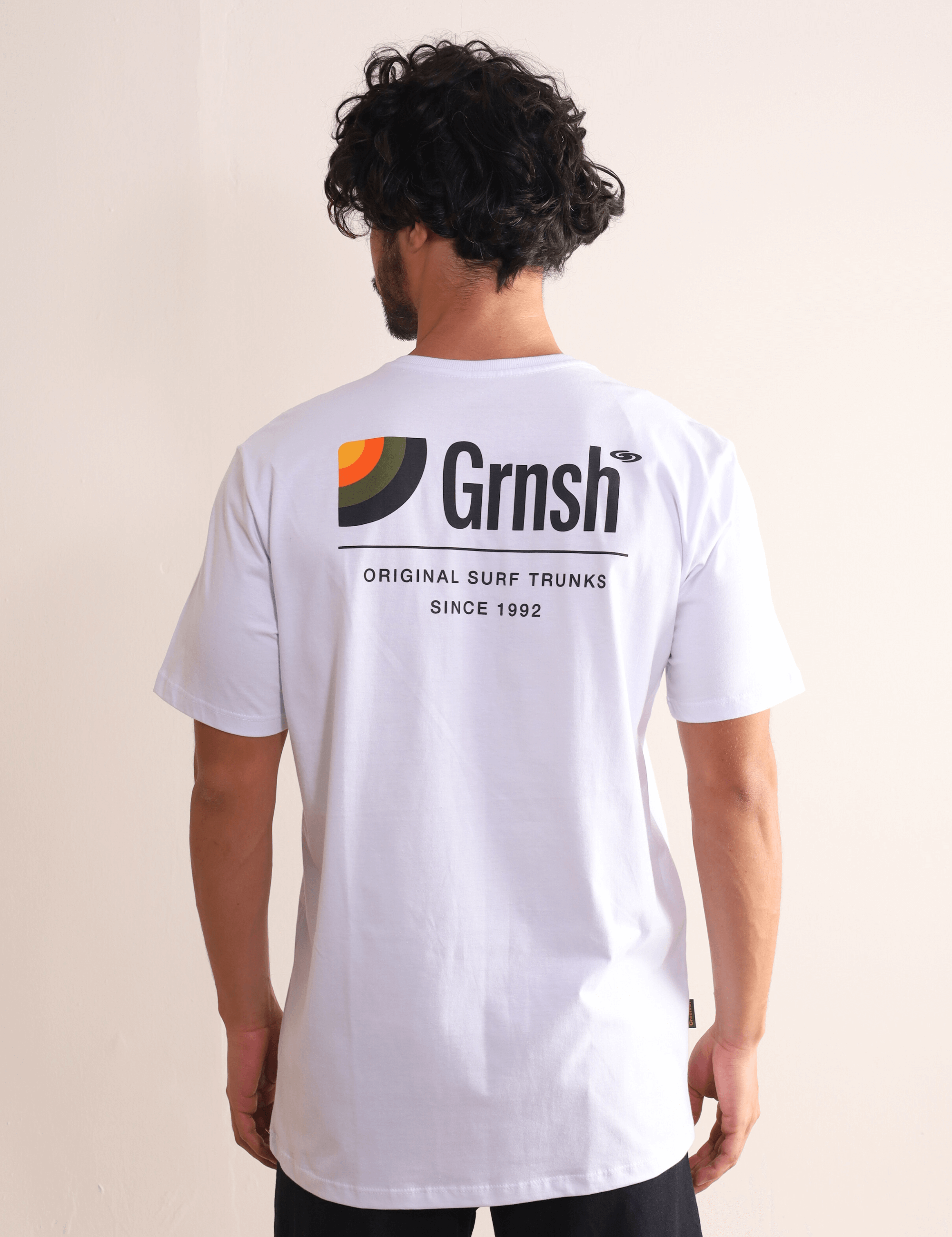 Camiseta Original Surf Trunks Series I - Branco da marca Greenish com estampa de surf lifestyle, usada por modelo de costas.