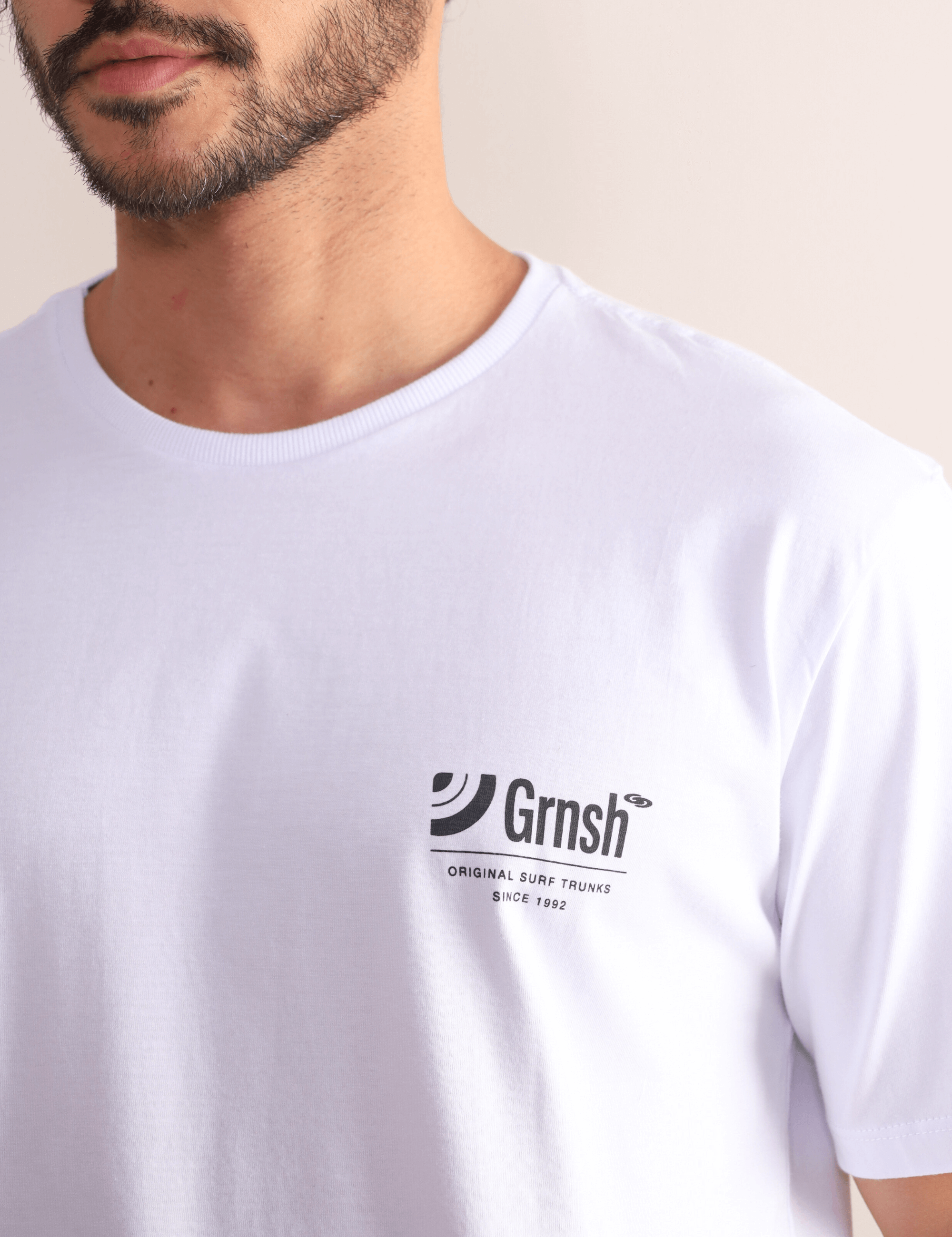 Homem usando camiseta branca Greenish Surf Trunks Series I, estilo litorâneo, confortável, com estampa frontal discreta.