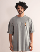 Alt Tag: Homem vestindo Camiseta Oversized Stone Surf Session - cinza da marca Greenish, com arte retrô em algodão.