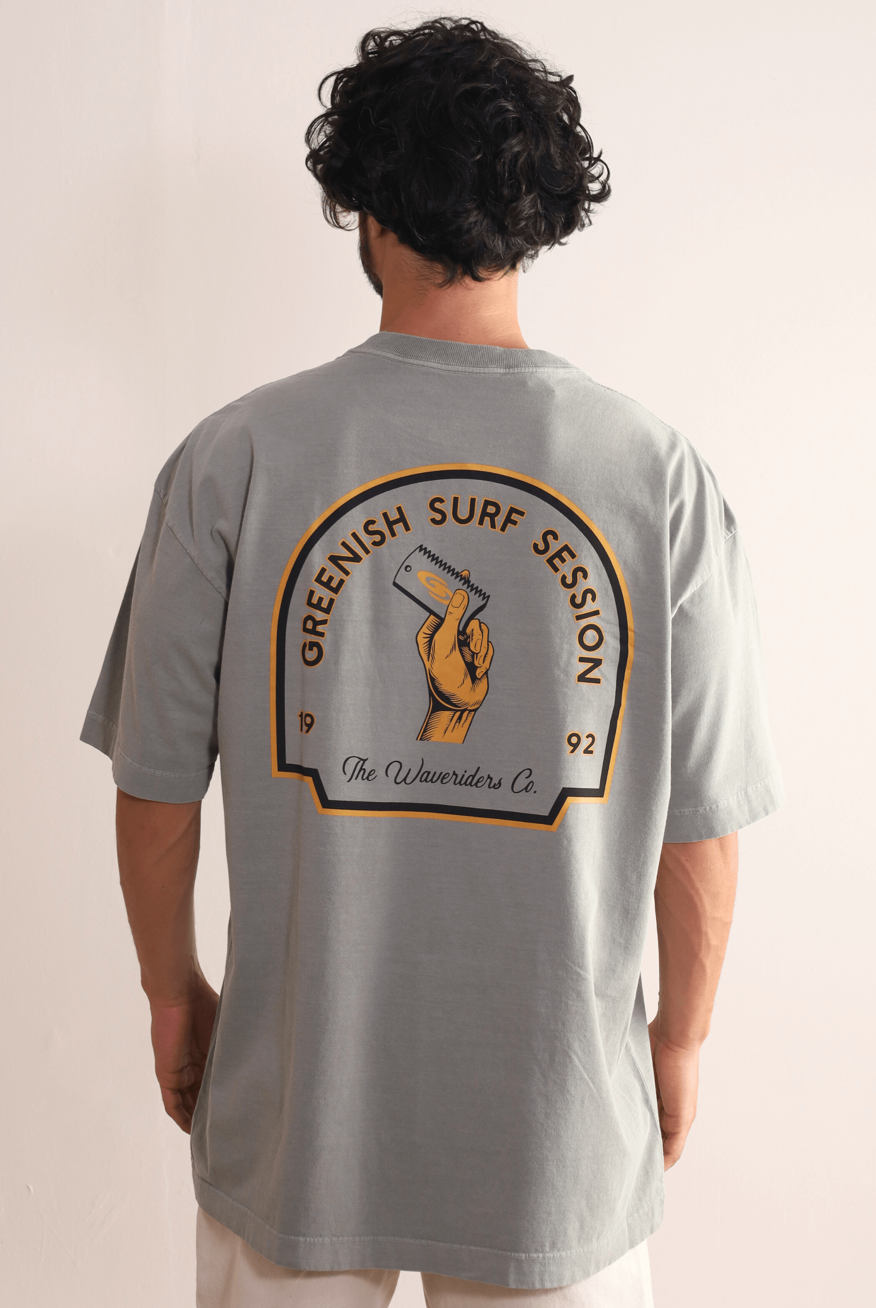 Homem vestindo Camiseta Oversized Stone Surf Session - cinza da marca Greenish com arte retrô nas costas, estilo despojado e moderno.