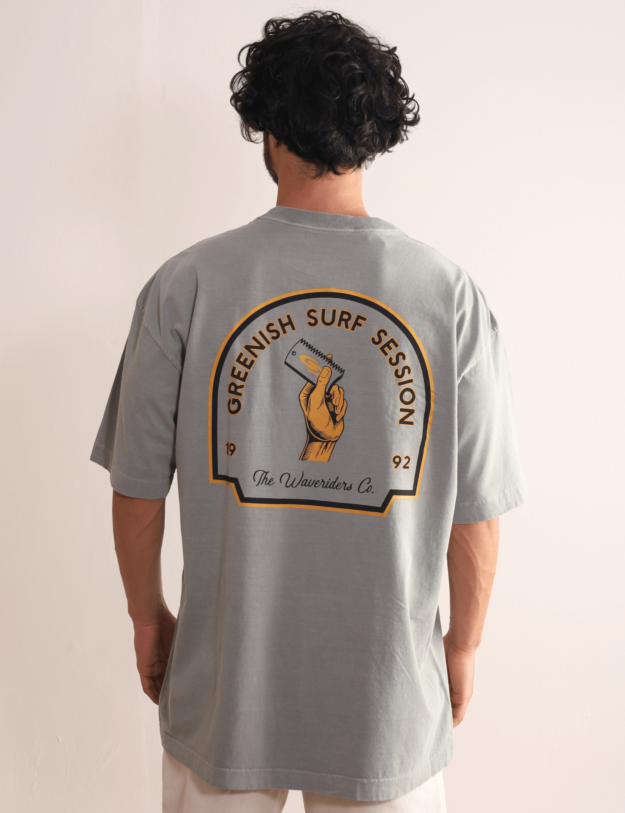 Homem vestindo Camiseta Oversized Stone Surf Session - cinza da marca Greenish com arte retrô nas costas, estilo despojado e moderno.