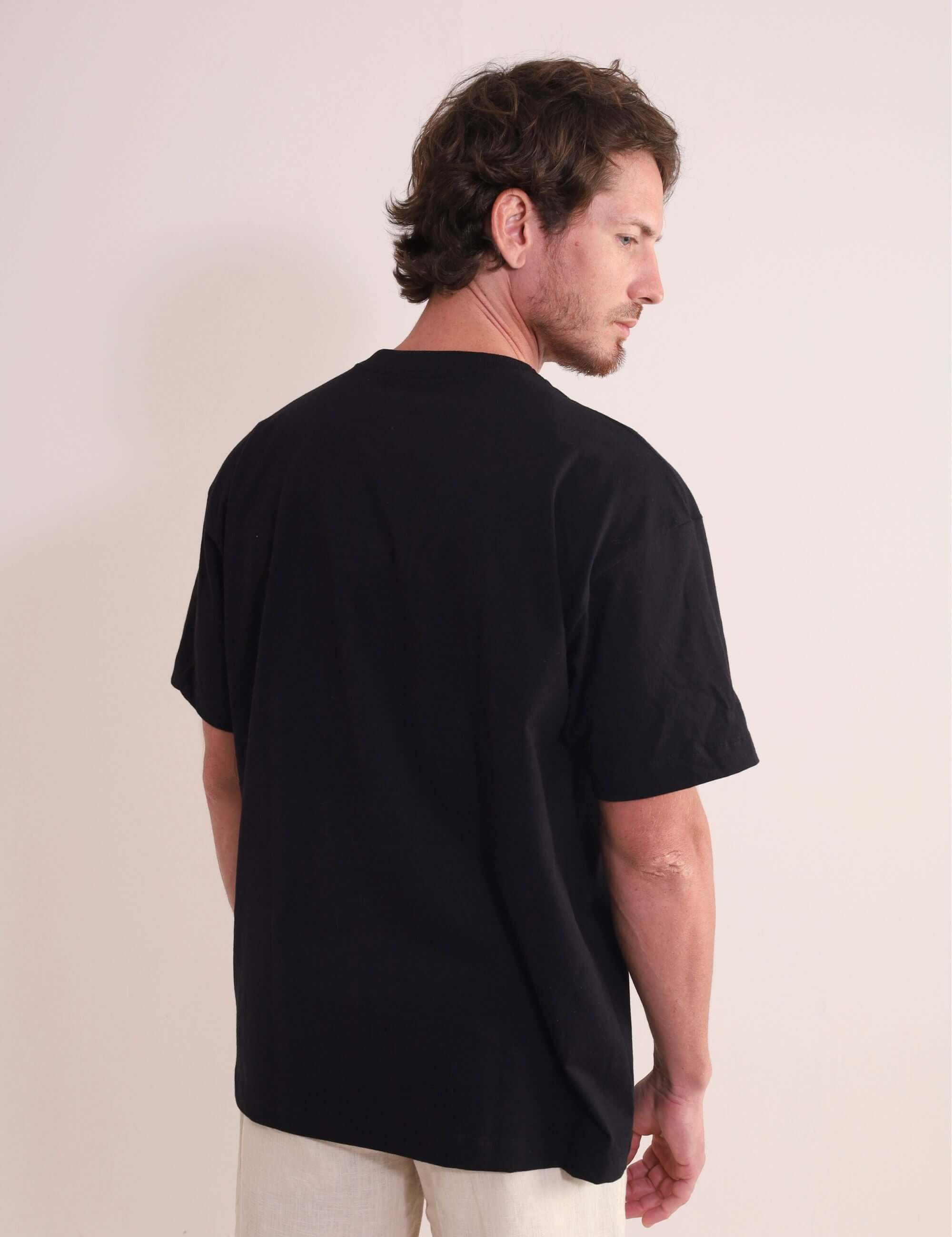 Homem usando Camiseta Oversized Strong - Preto da marca Greenish, destacando a autenticidade e conforto da peça em algodão com gola ribana.