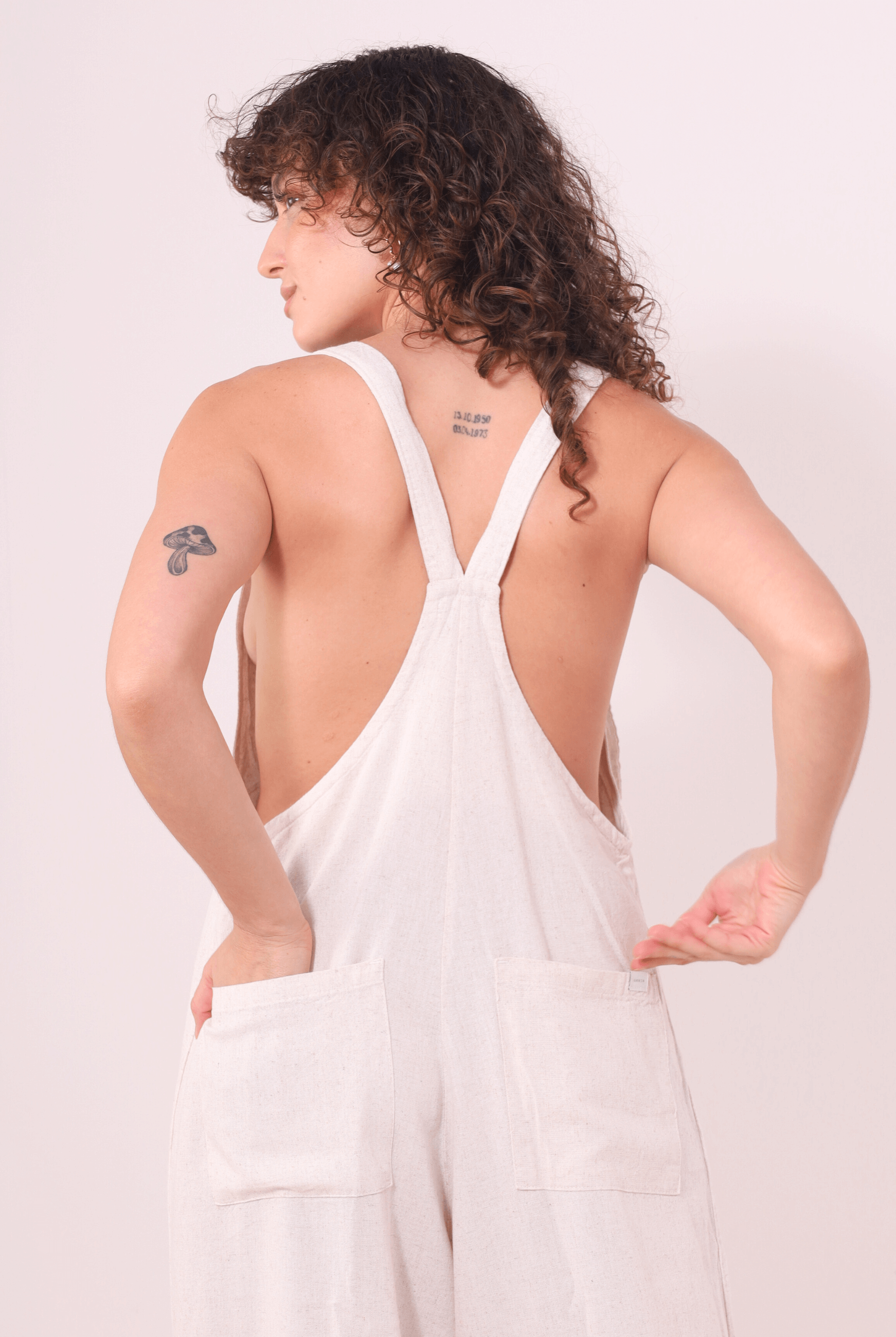 Pessoa usando o Macacão Khay - Natural da Greenish, em Linho Washed Soft, com costas nadador e bolsos traseiros para praticidade e estilo.