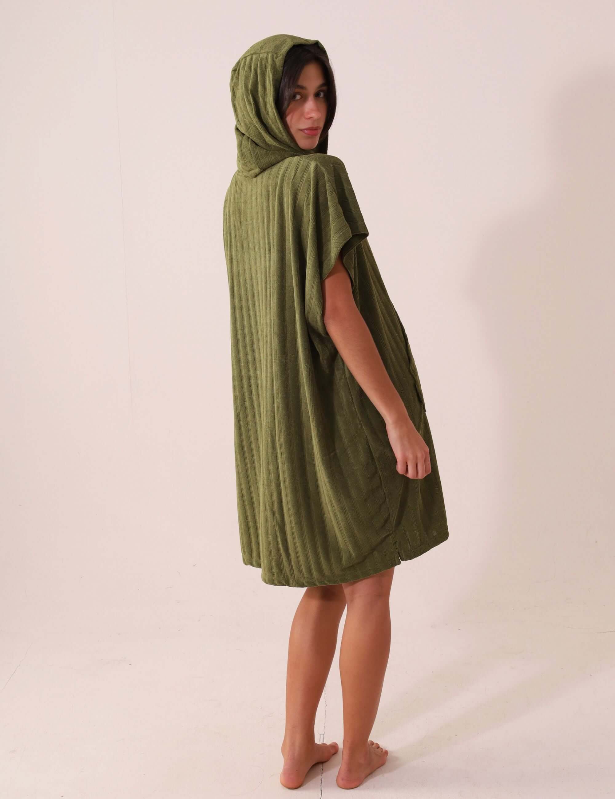 Modelo usando PONCHO CURTO CANELADO - VERDE da Greenish, ideal para praia, com bolsos canguru e tecido atoalhado de rápida secagem.