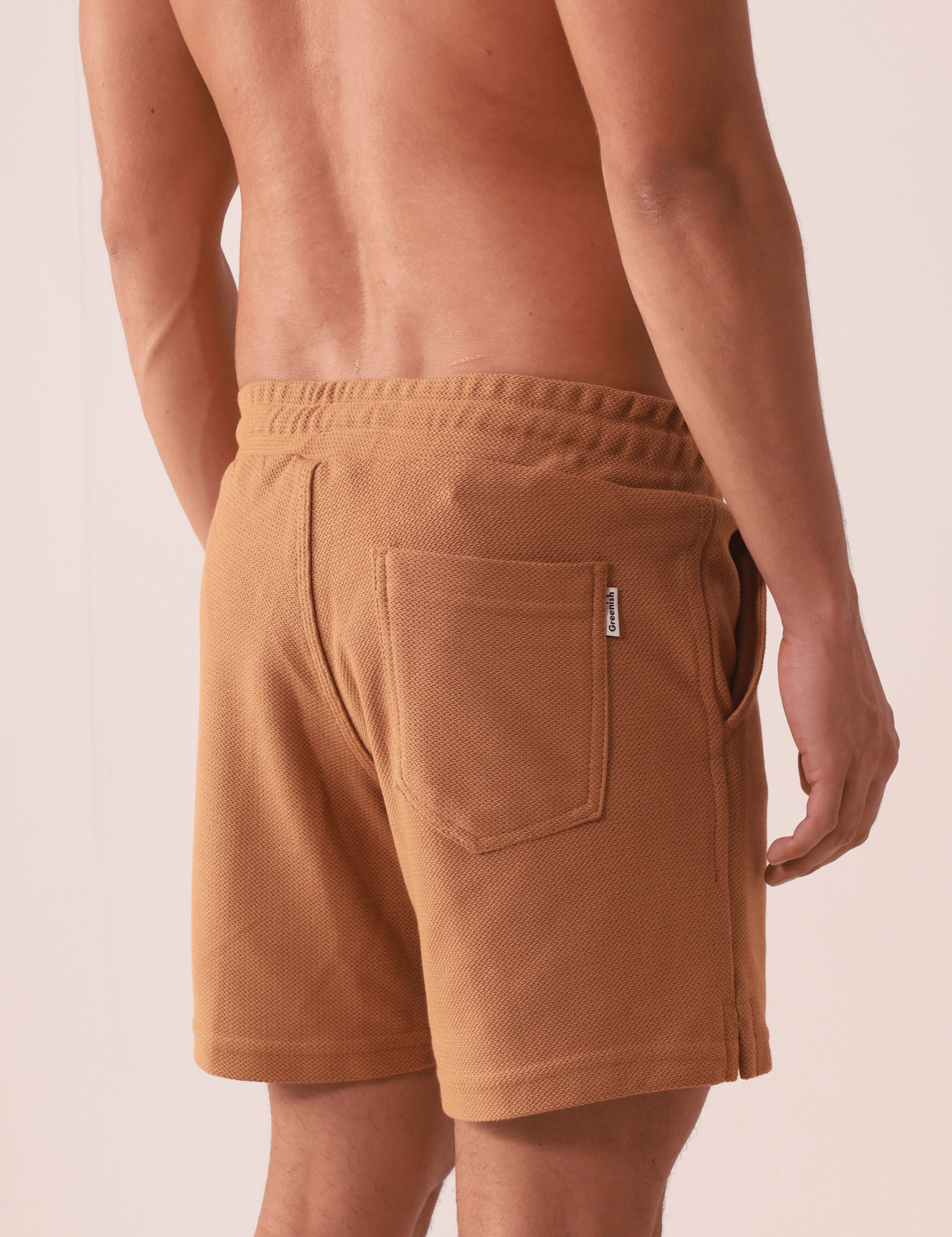 Homem vestindo SHORT MOLETOM ARTISAN - AMARELO ESCURO da Greenish, mostrando detalhes do bolso chapado traseiro e cós elástico.