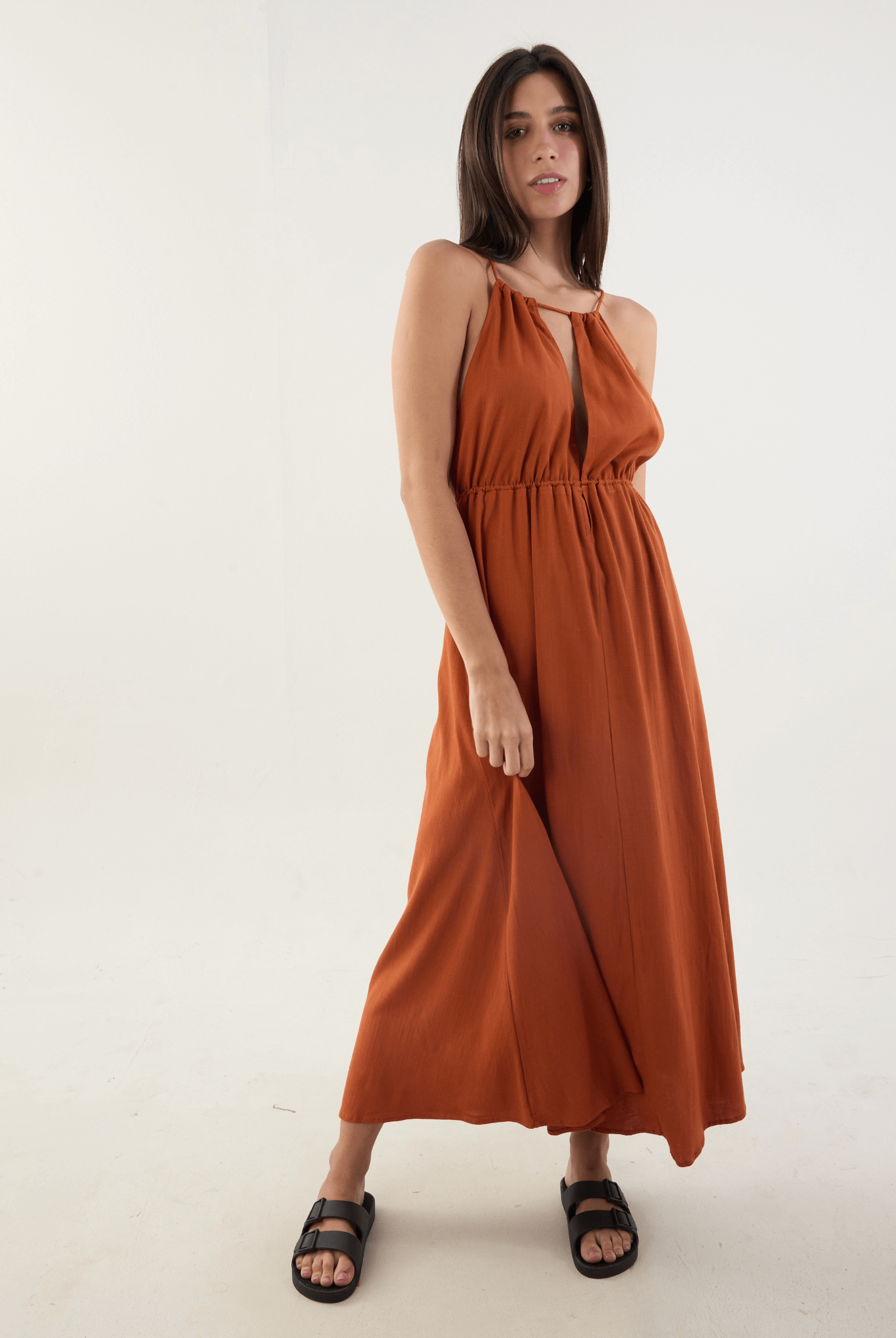 Mulher vestindo o Vestido Longo Gaia na cor telha por Greenish, com design fluido, alças ajustáveis e toque macio, ideal para dias de sol.