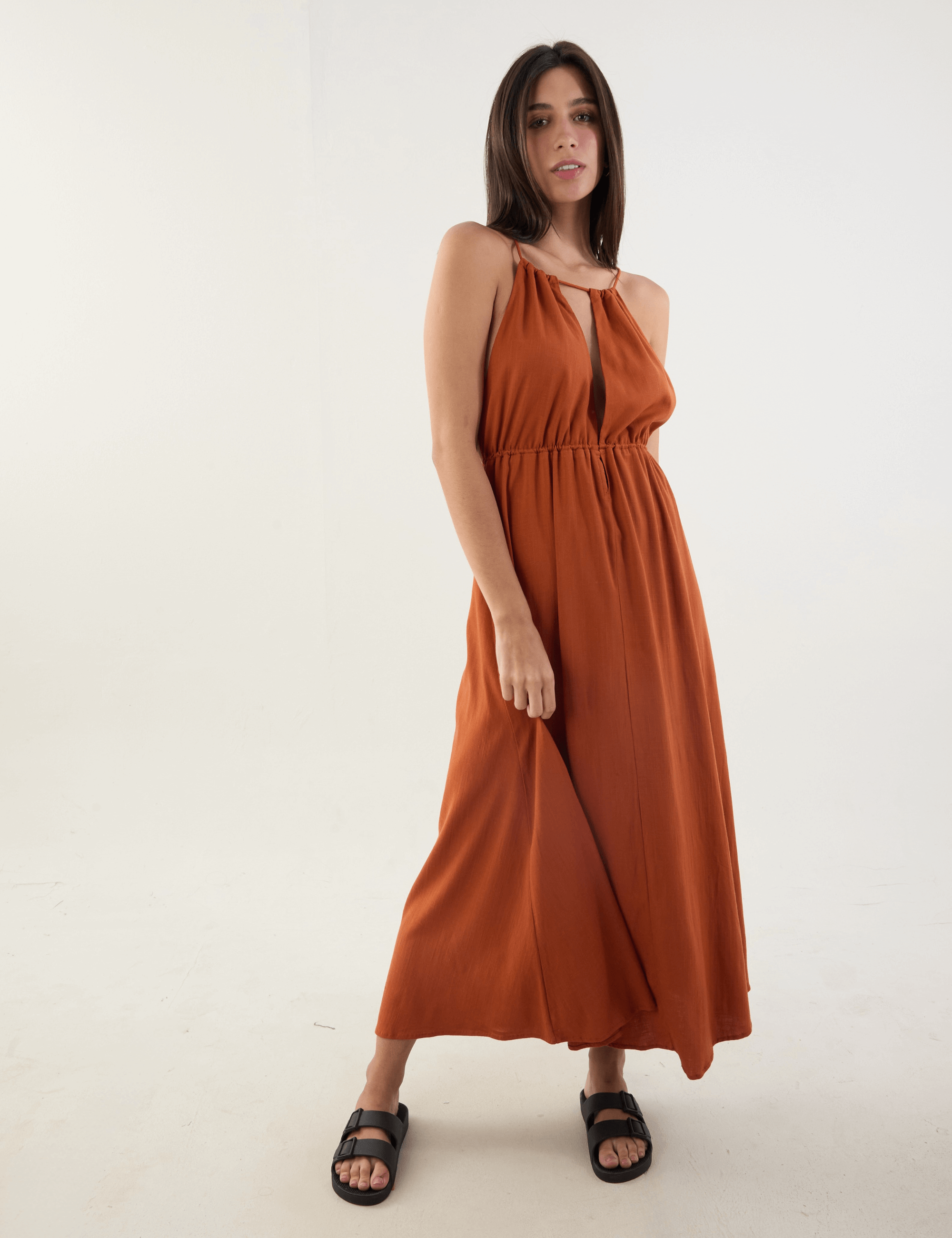 Mulher vestindo o Vestido Longo Gaia na cor telha por Greenish, com design fluido, alças ajustáveis e toque macio, ideal para dias de sol.