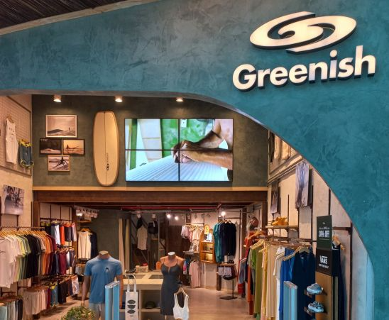 Loja Greenish com roupas de surfe, prancha e tela mostrando detalhes de pranchas!