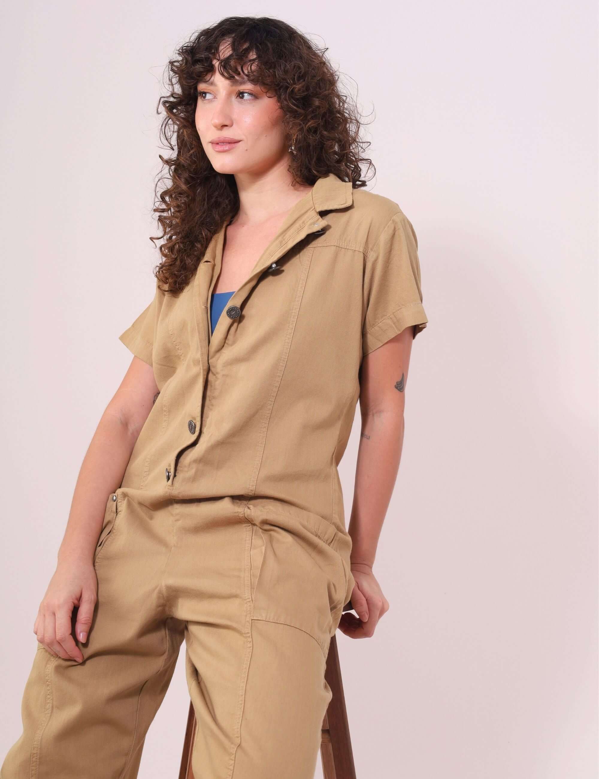 Mulher usando Macacão Ivy Bege em sarja da marca Greenish, estilo utilitário, prático e confortável, ideal para looks urbanos e naturais.