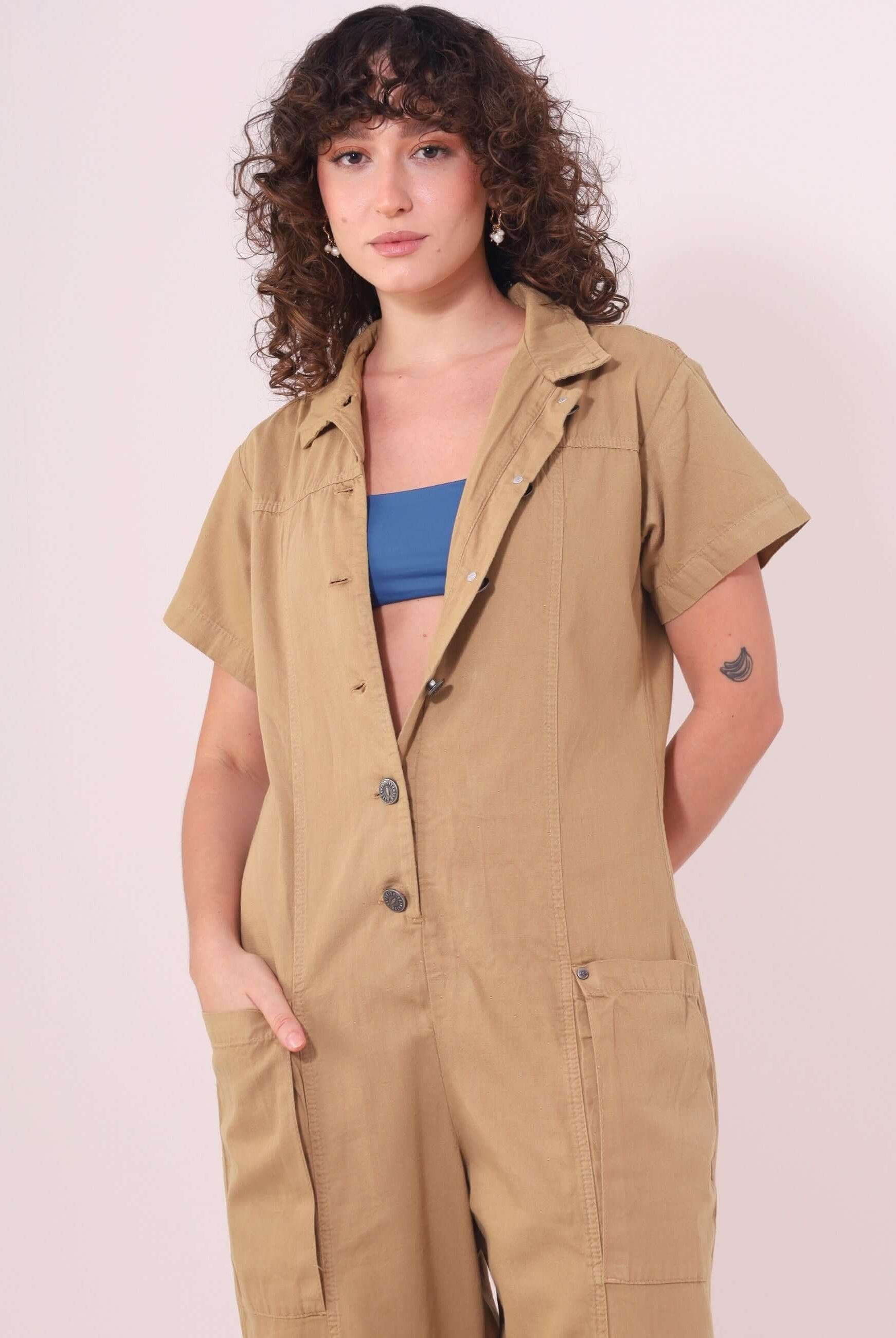 Mulher usando macacão Ivy bege da Greenish, estilo utilitário e confortável, com mangas e bolsos, feito de sarja 100% algodão.