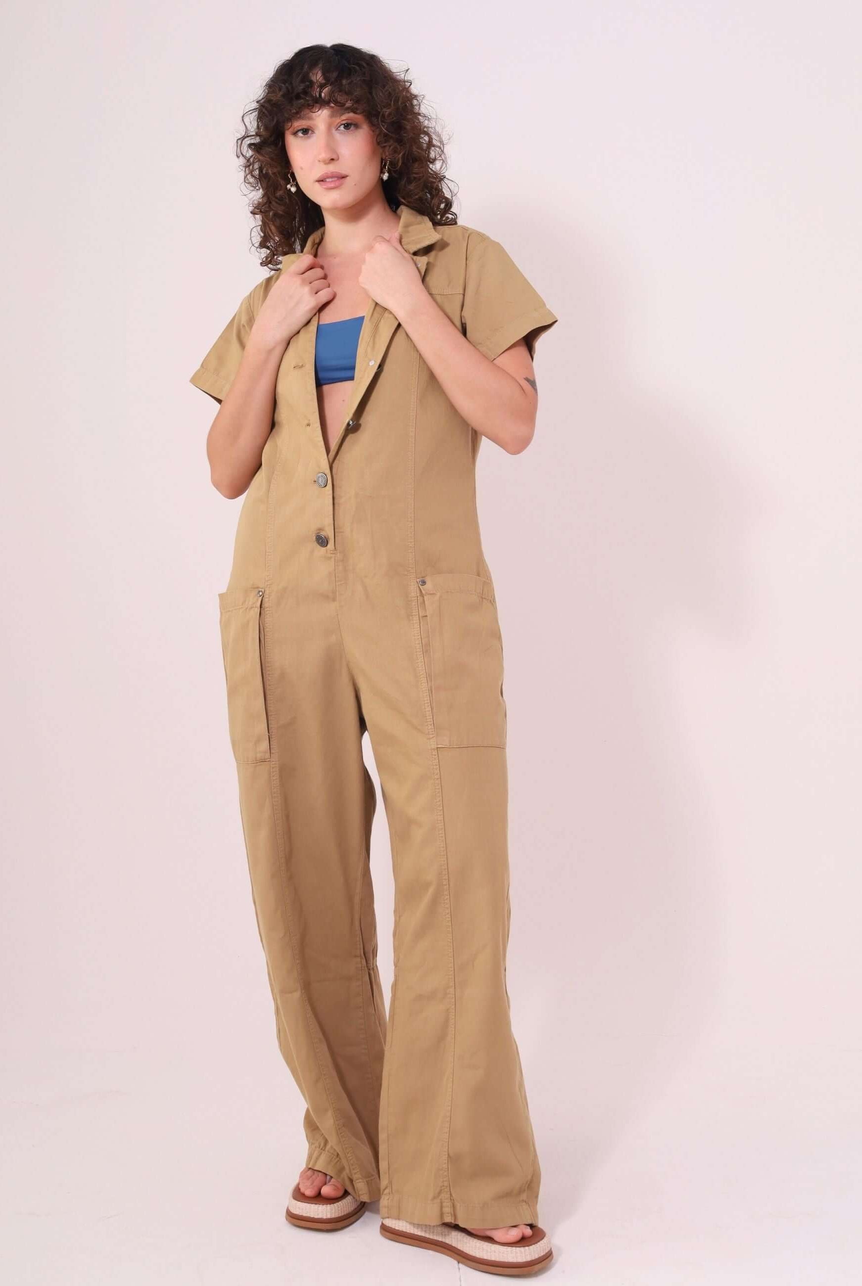 Mulher vestindo Macacão Ivy Bege da Greenish, em sarja 100% algodão, com mangas, gola estruturada e fechamento frontal com botões.