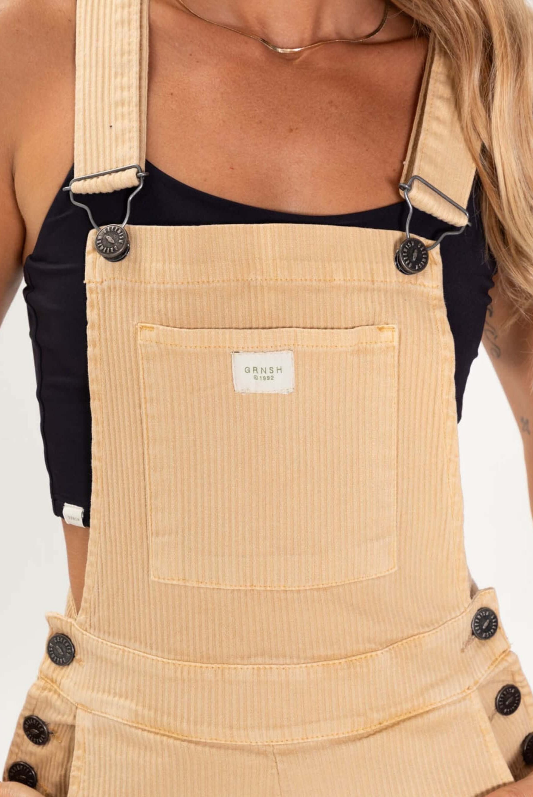 Macacão jardineira Suy da Greenish em amarelo claro, caimento soltinho, alças reguláveis e botões de metal.