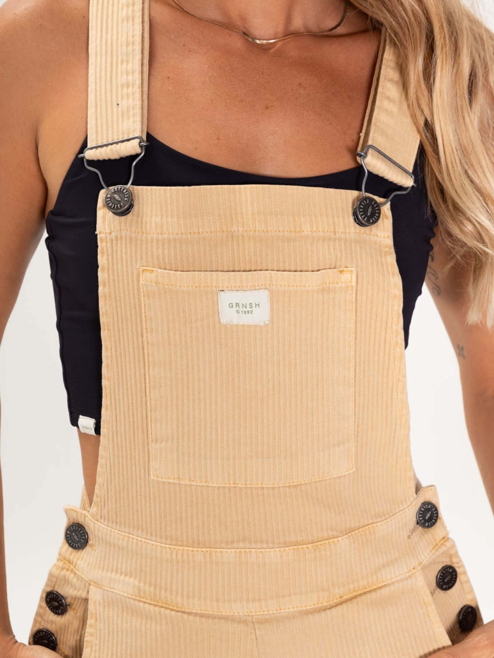 Macacão jardineira Suy da Greenish em amarelo claro, caimento soltinho, alças reguláveis e botões de metal.