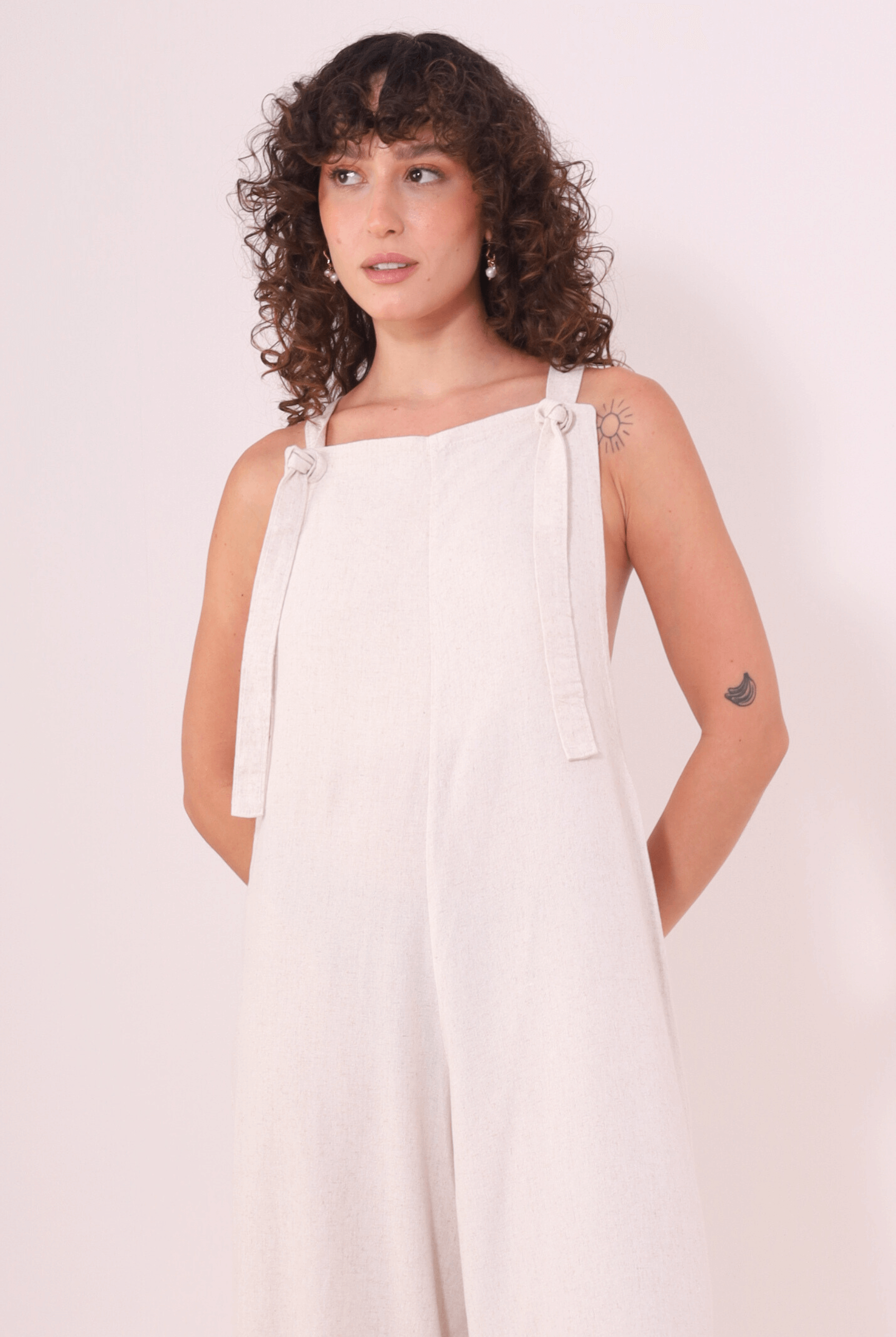 Mulher vestindo Macacão Khay - Natural da marca Greenish, feito de linho lavado macio, com design cavado e costas nadador, ideal para o verão.