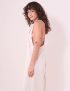 Mulher usando o Macacão Khay - Natural da Greenish em linho, com costas nadador e alças ajustáveis, destacando design e conforto.