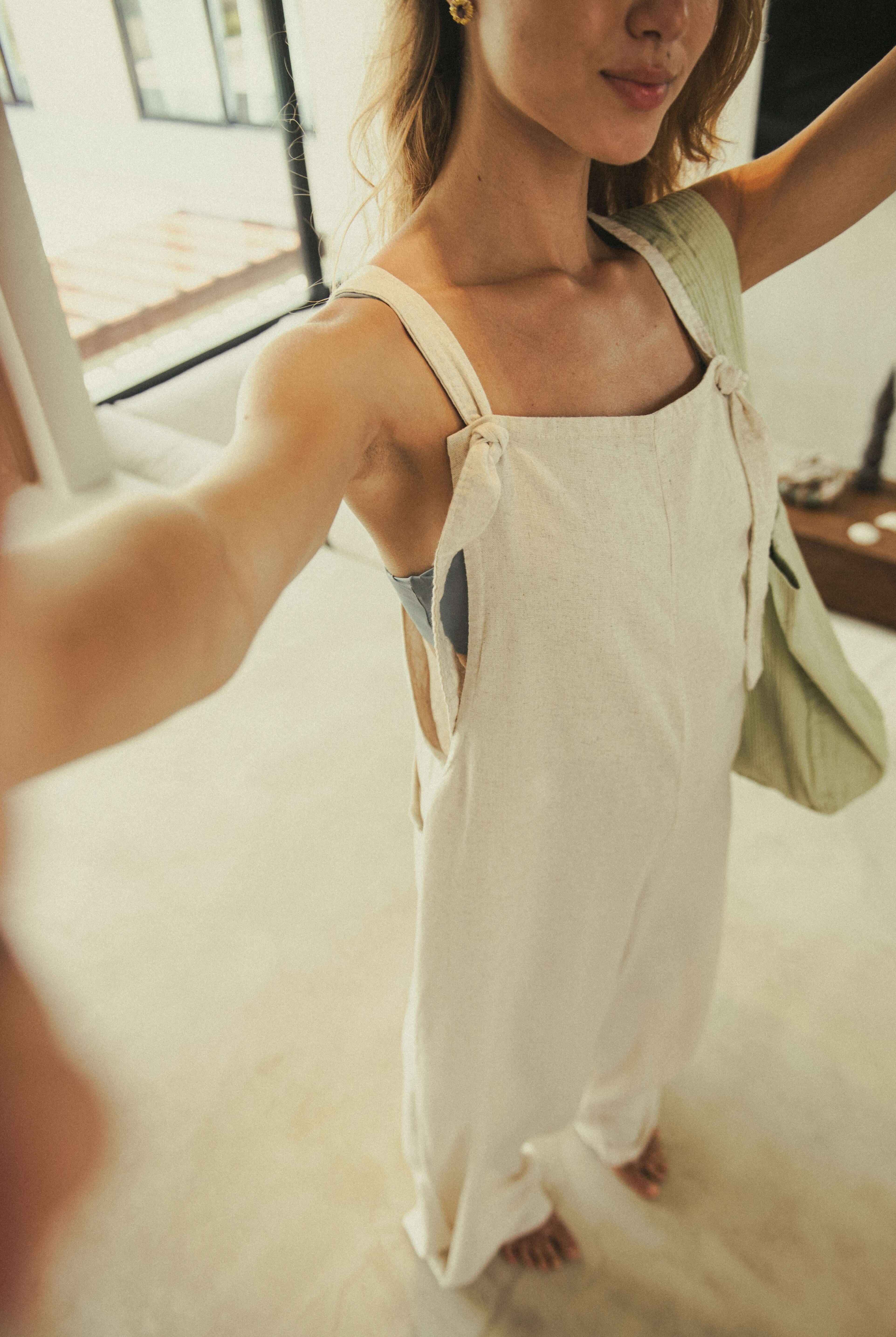 Mulher vestindo o Macacão Khay - Natural da Greenish, em linho suave, ideal para dias quentes e momentos de descontração.