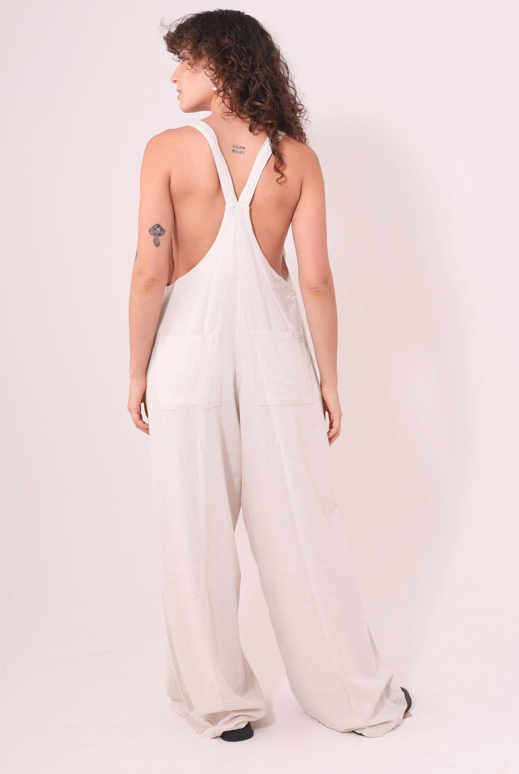 Modelo vestindo Macacão Khay - Natural da marca Greenish em linho, com design moderno e costas nadador, ideal para dias quentes.
