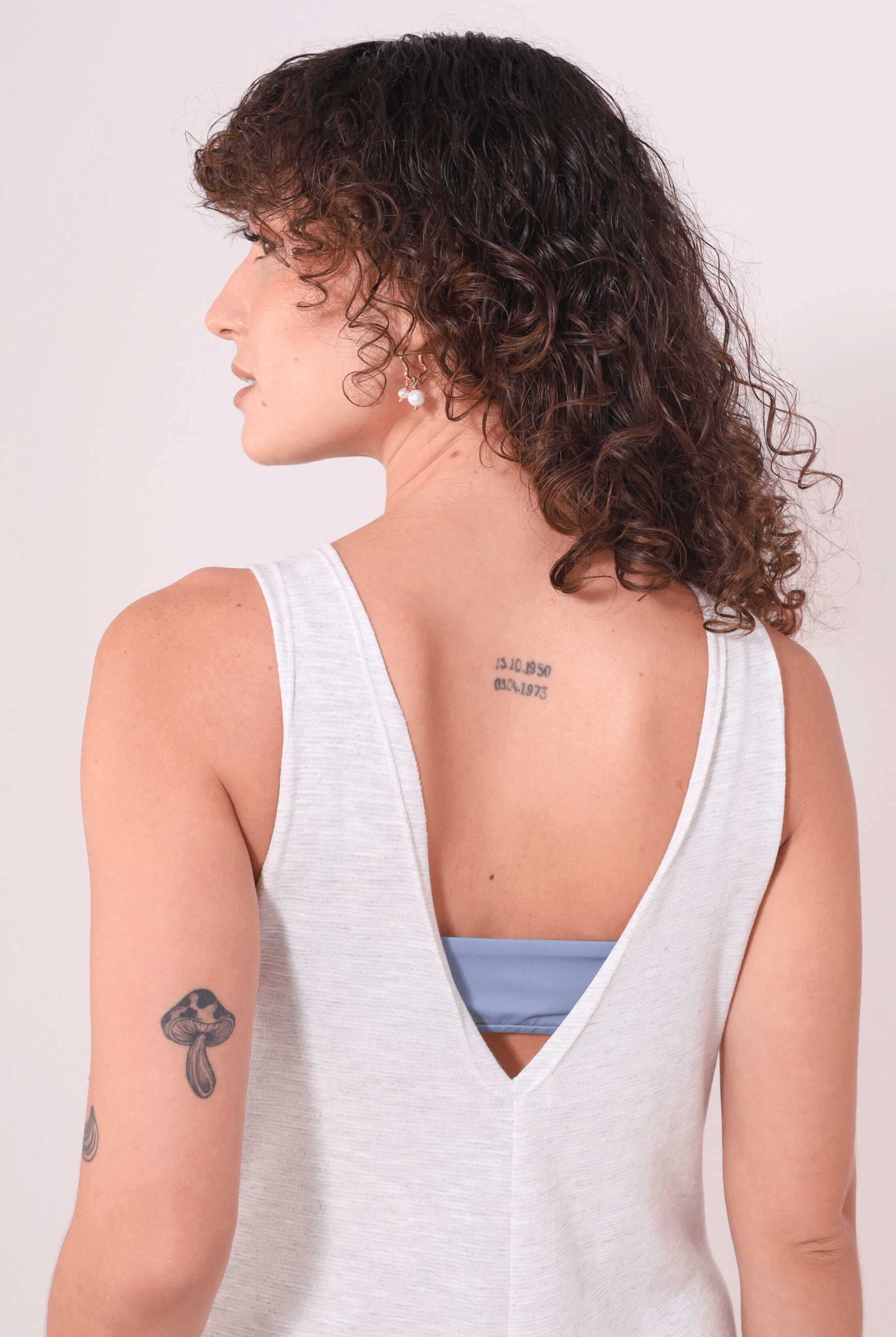 Mulher vestindo Macacão Lais Natural da Greenish, com decote em V nas costas, destacando o estilo leve e conforto do verão.