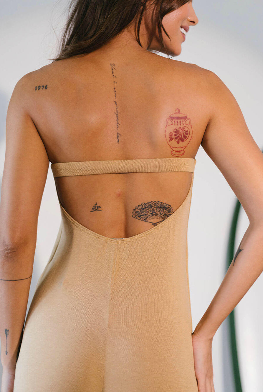 Macacão Larissa bege da Greenish, com costas nuas e tatuagens visíveis, mostrando estilo e conforto.
