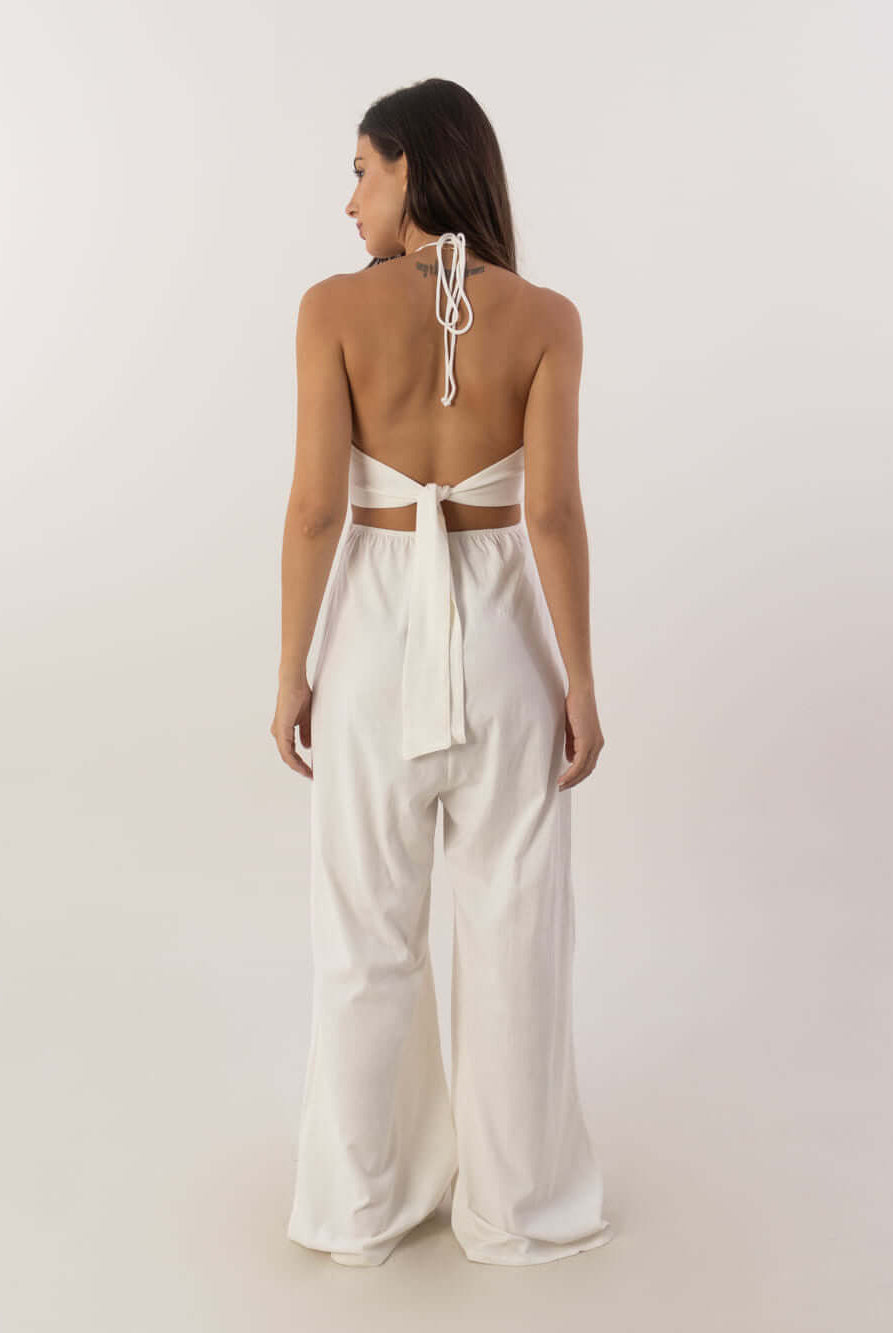 Mulher mostrando o macacão longo Alyssa off white da Greenish, com decote em V e amarração nas costas.