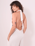 Mulher usando Macacão Longo Gaia - Natural da Greenish, de Linho Washed Soft, com faixas no pescoço e design fluido.