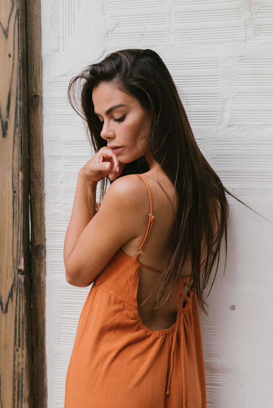 Modelo usando o macacão Mabel laranja da Greenish, com decote nas costas e alças reguláveis, perfeito para o verão.