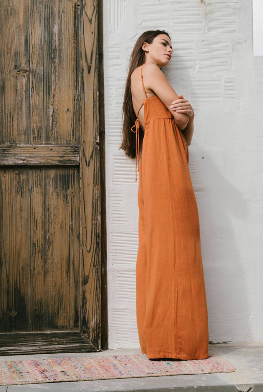 Modelo usando o macacão Mabel laranja da Greenish, com caimento solto e decote quadrado, elegante e confortável.