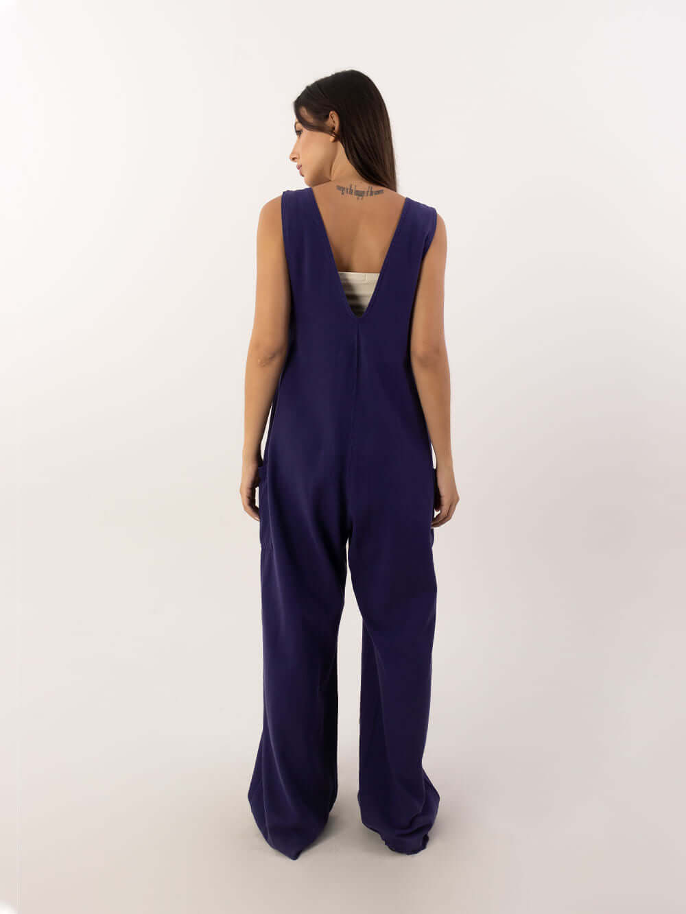 Mulher usando o macacão Nath azul marinho da marca Greenish, vista traseira, estilo moderno e confortável.