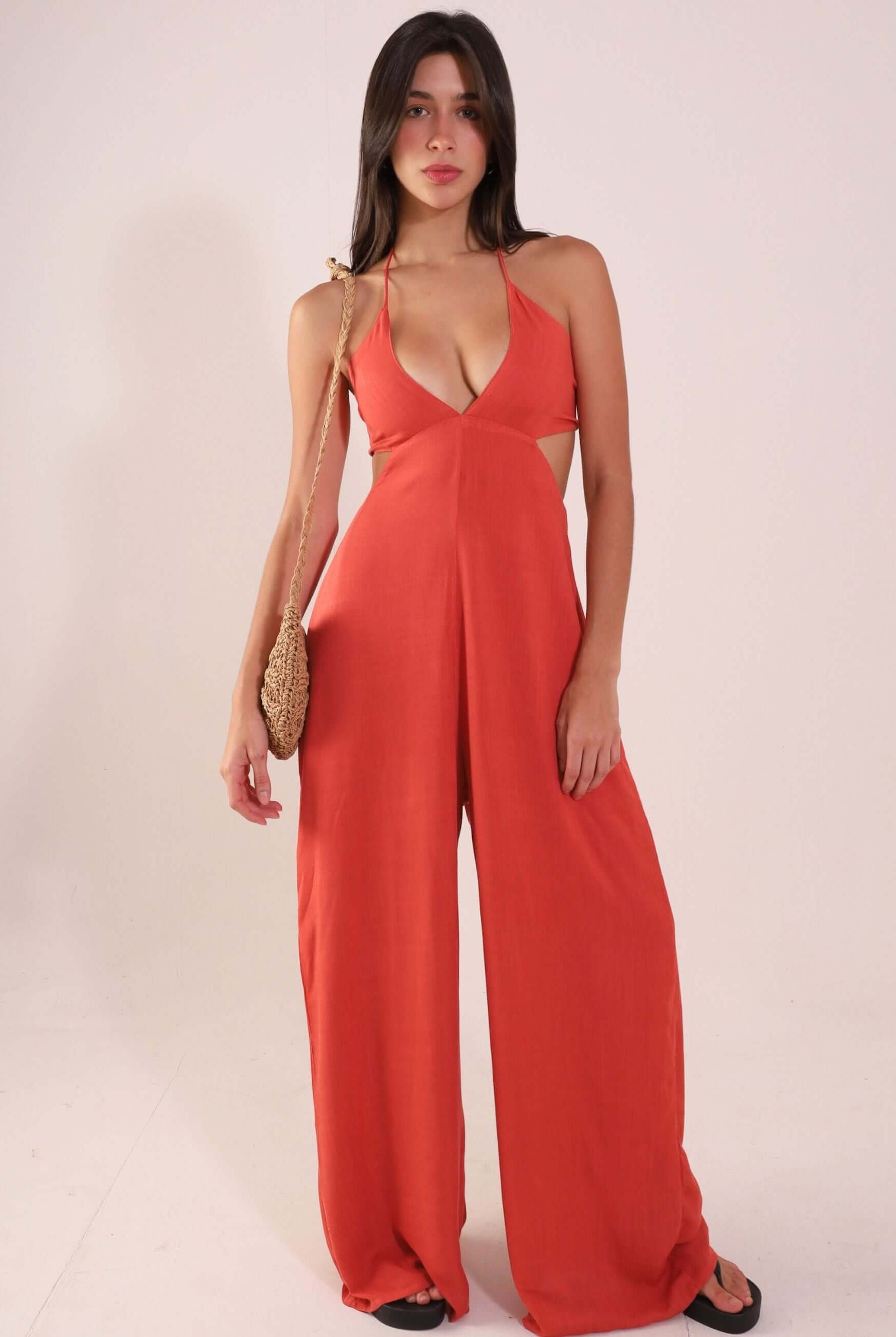 Woman wearing Macacão Rustic - Telha, a stylish and breathable rust-colored jumpsuit with V-neck and adjustable back ties.