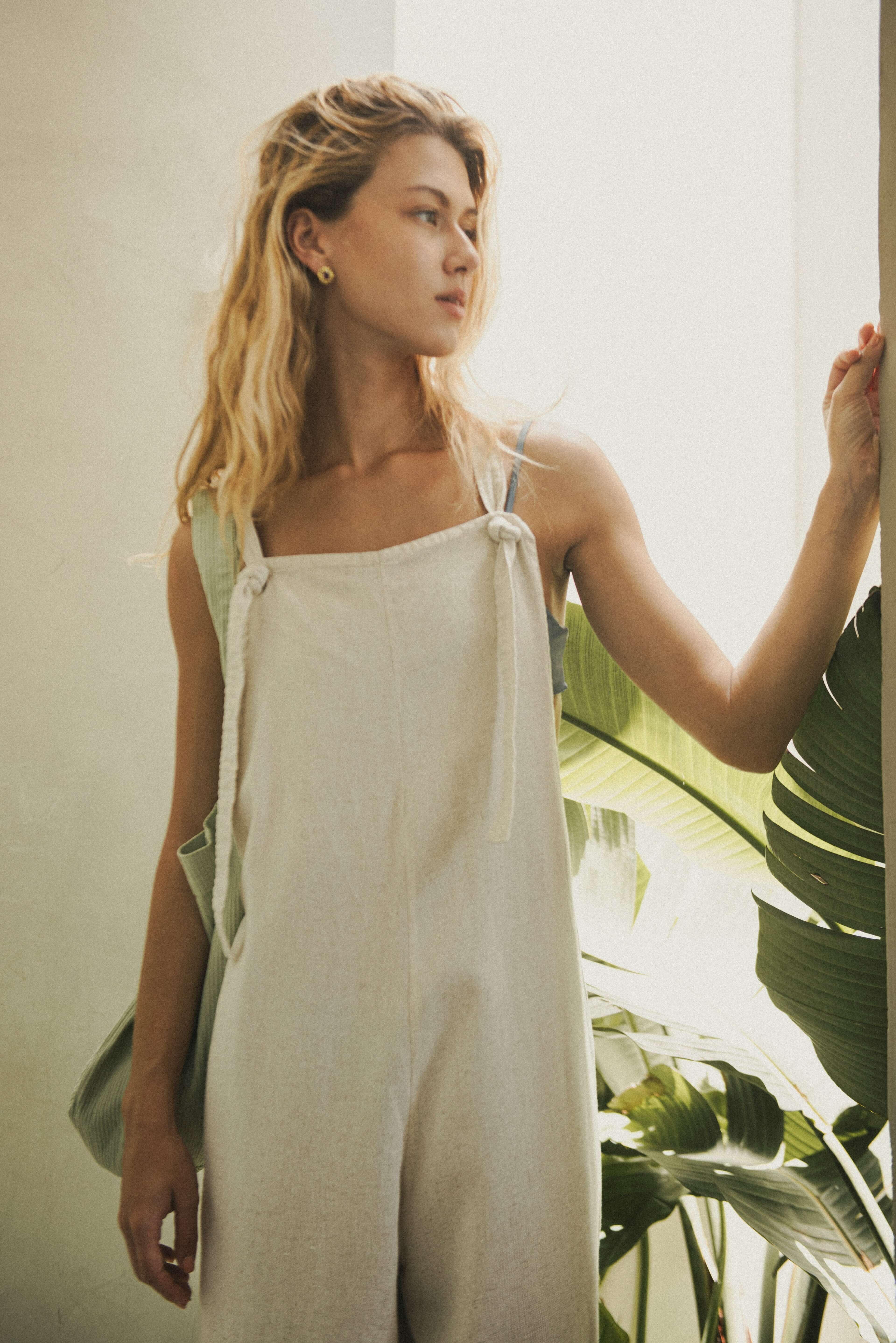 Modelo vestindo Macacão Khay - Natural da Greenish, feito em Linho Washed Soft com costas nadador e alças ajustáveis.