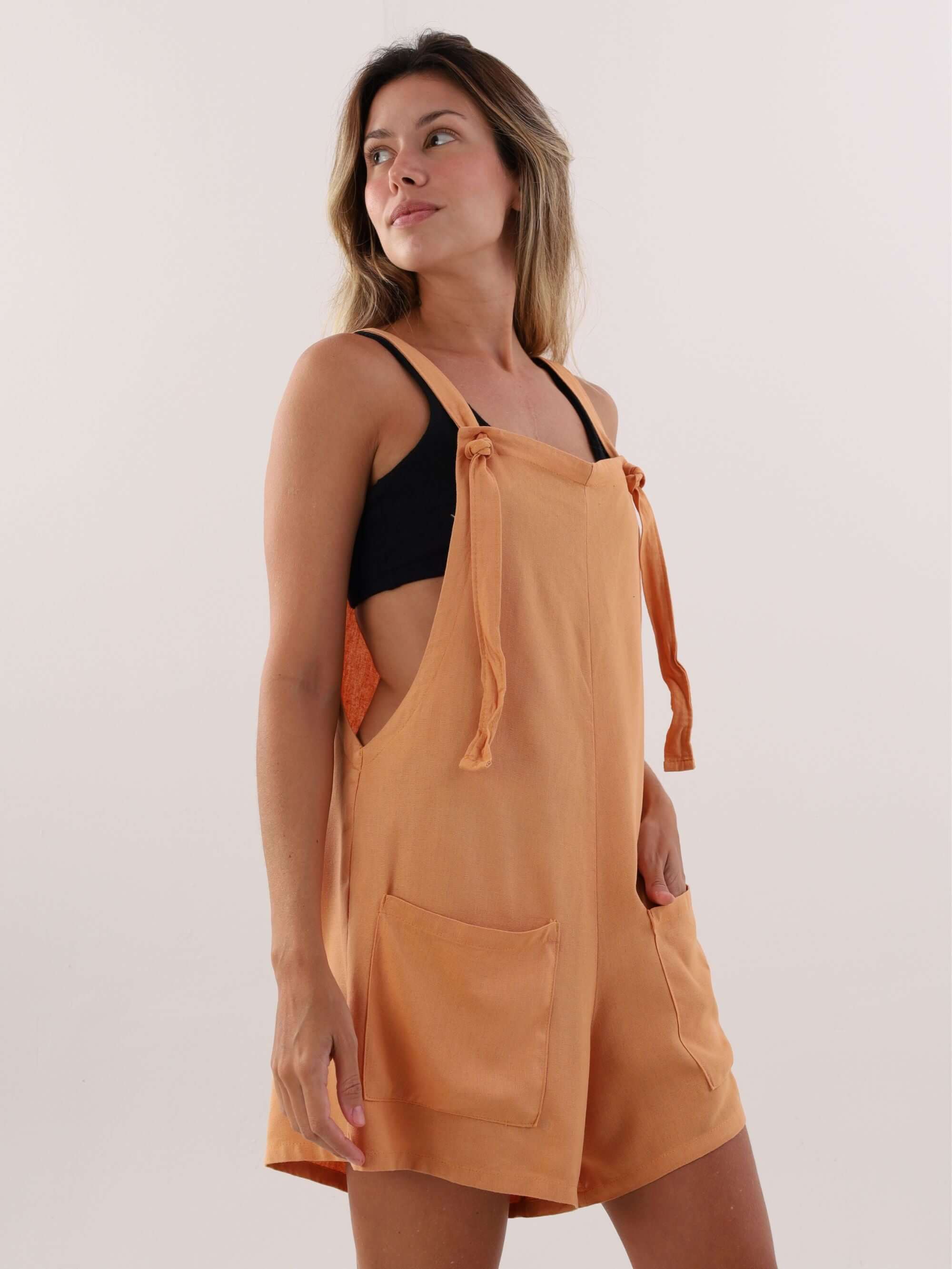 Macaquinho Quinn laranja da marca Greenish, com design solto, alças reguláveis e bolsos frontais, ideal para looks casuais.