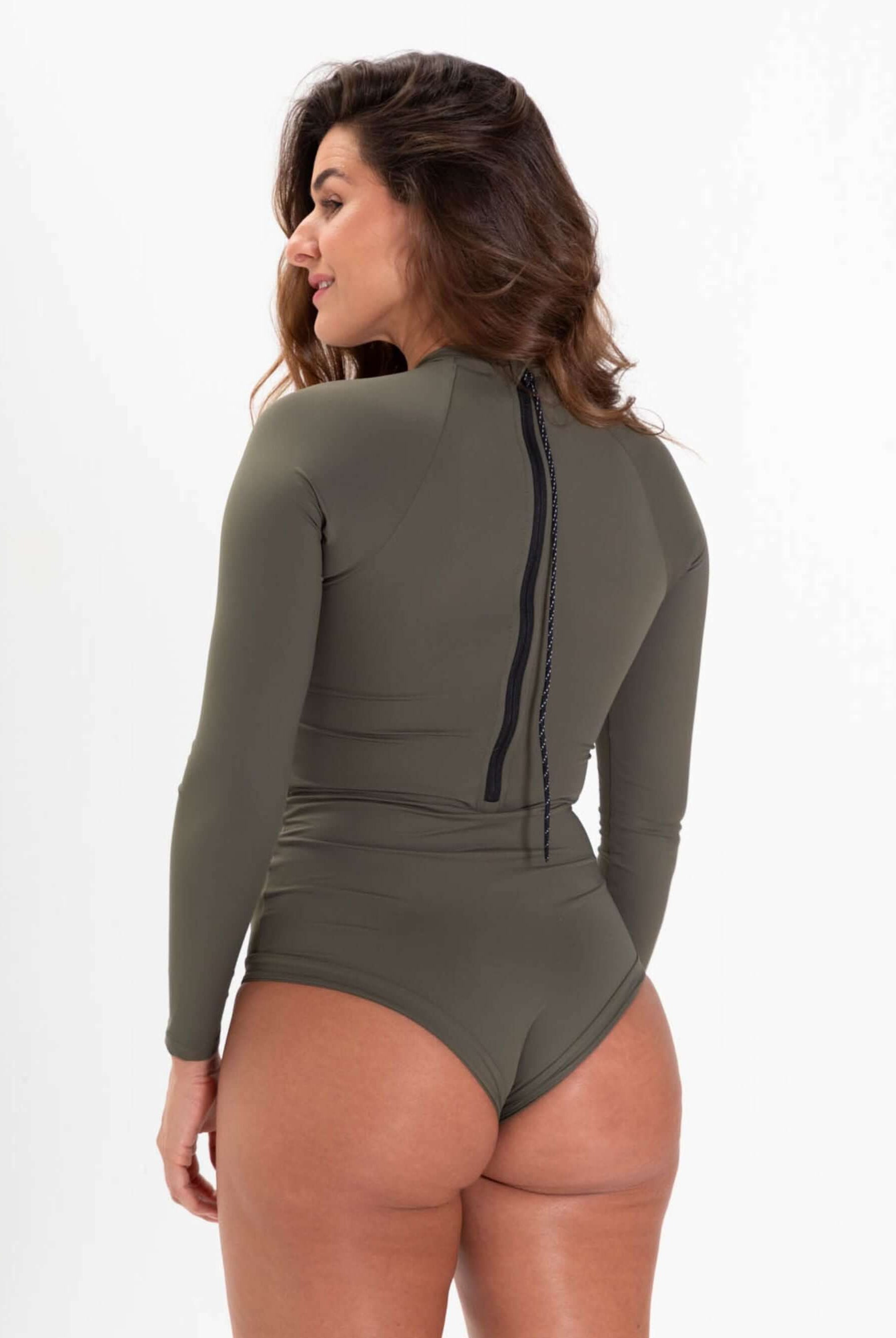 Mulher usando maiô verde com mangas longas, fechamento em zíper nas costas e design confortável.