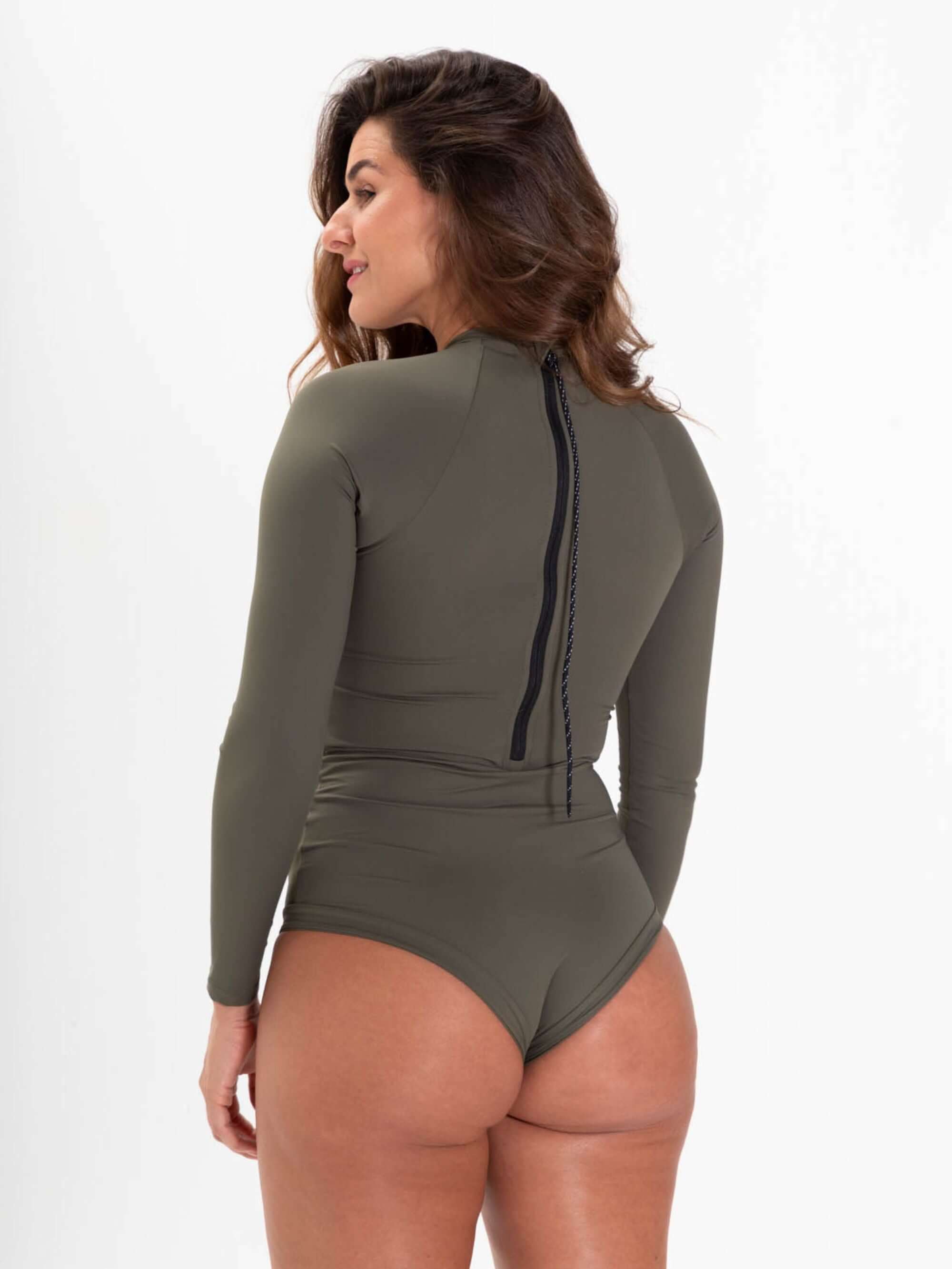 Mulher usando maiô verde com mangas longas, fechamento em zíper nas costas e design confortável.