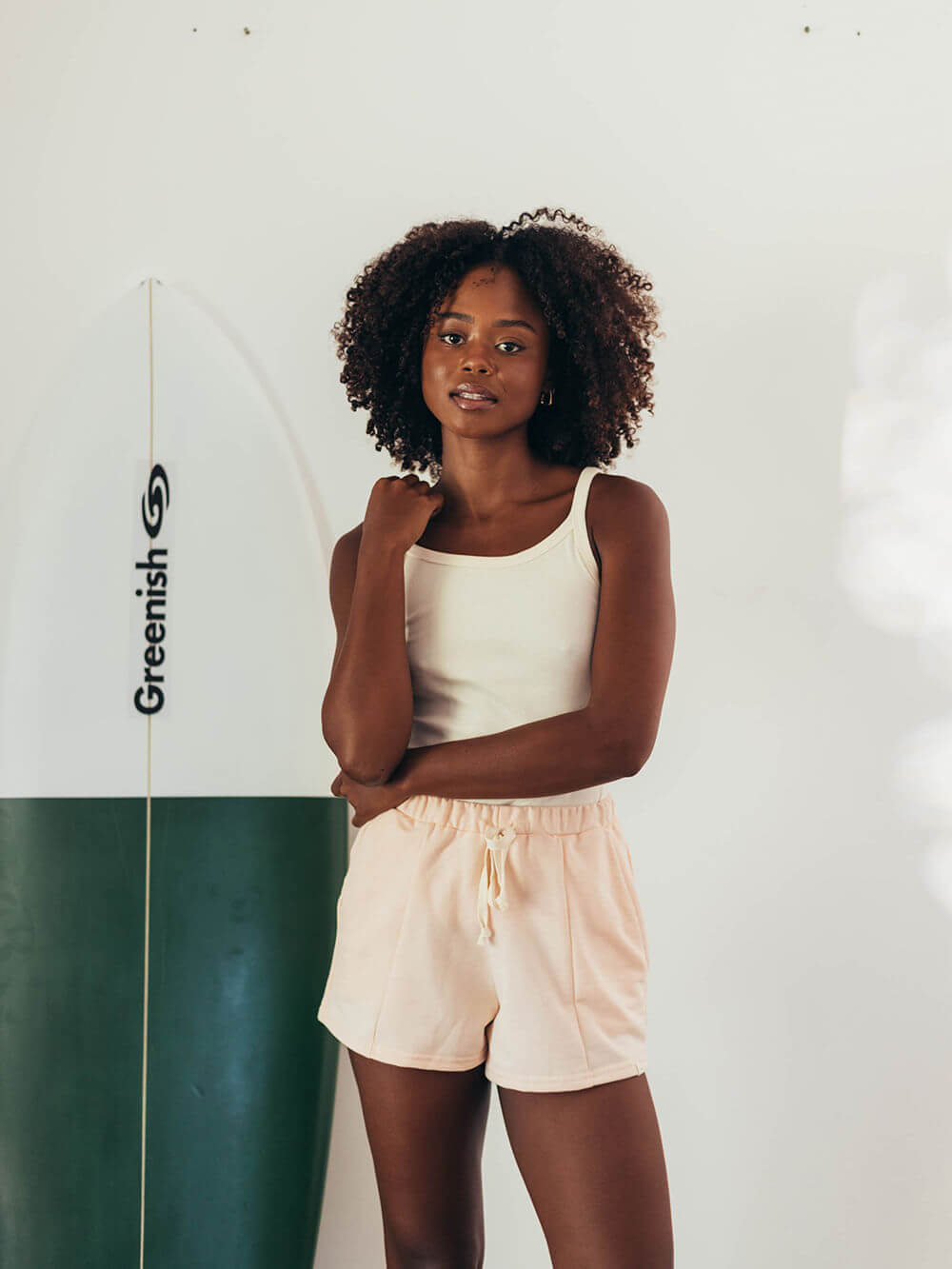 Moletom Clay laranja da Greenish, modelo solto e confortável, perfeito para o dia a dia, com a surfista ao fundo.