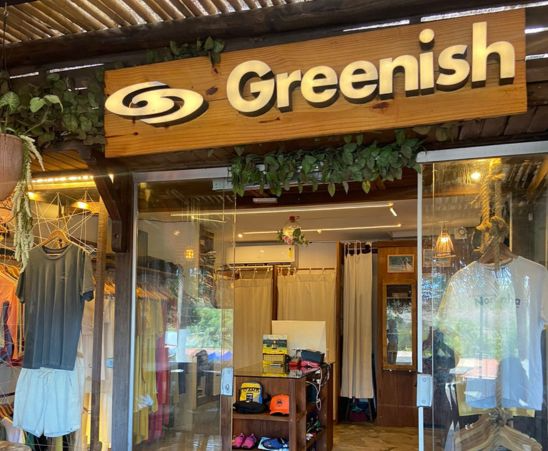 Entrada da loja Greenish, destacando roupas e acessórios em um ambiente aconchegante.
