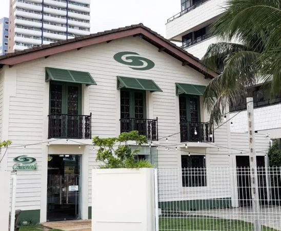 Fachada de uma casa de estilo colonial com janelas verdes, localizada em uma rua tranquila.