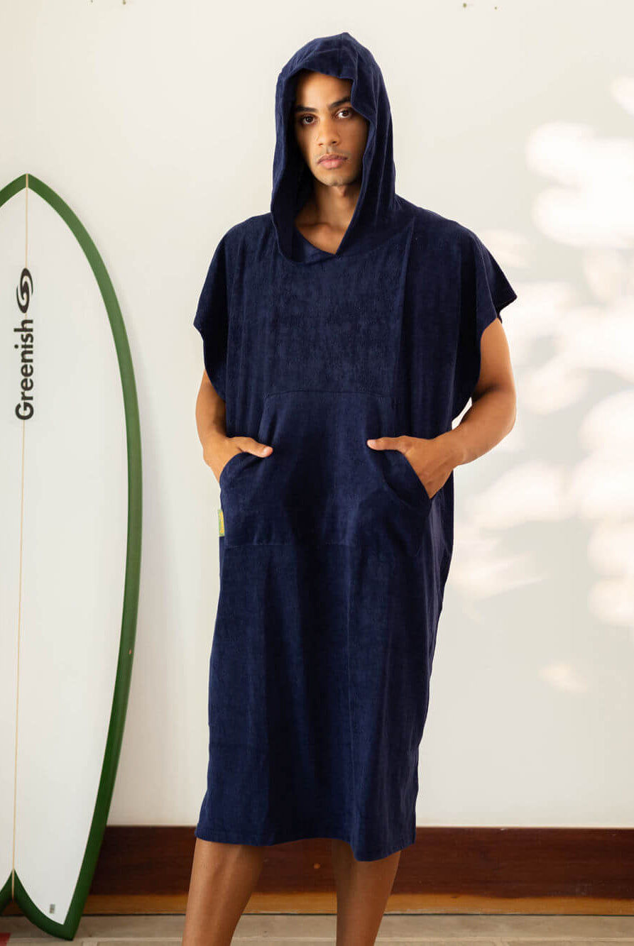 Modelo usando o Poncho Adulto Canguru Azul Marinho da Greenish, com capuz e bolsos, ideal para a praia.